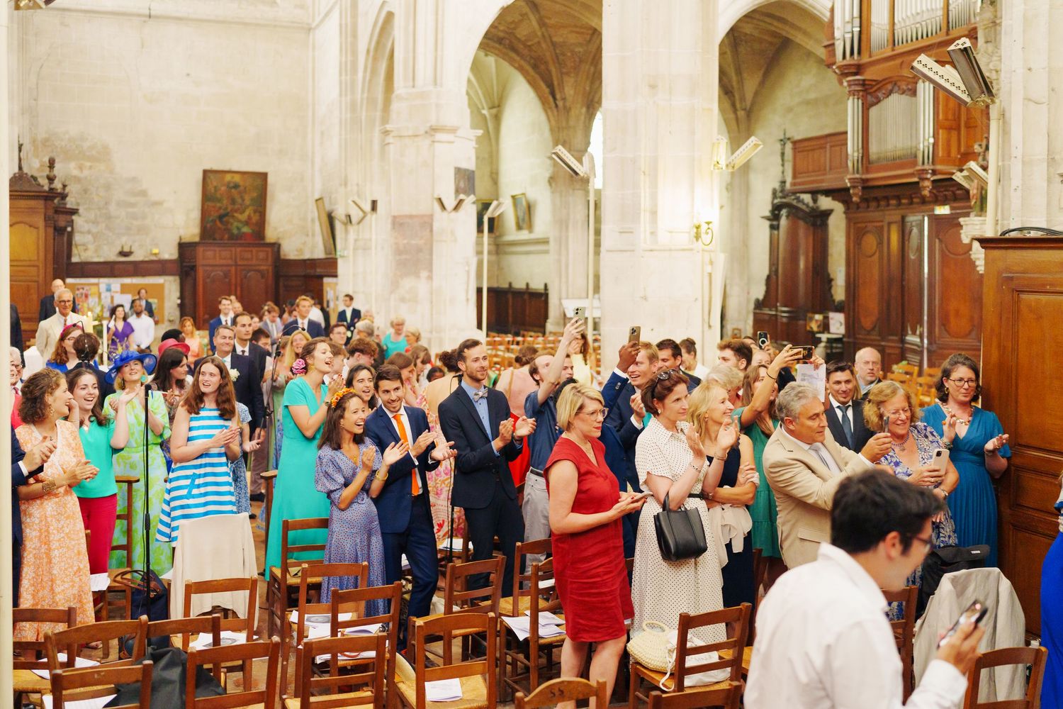 Church interior filled with wedding guests seated in wooden pews.