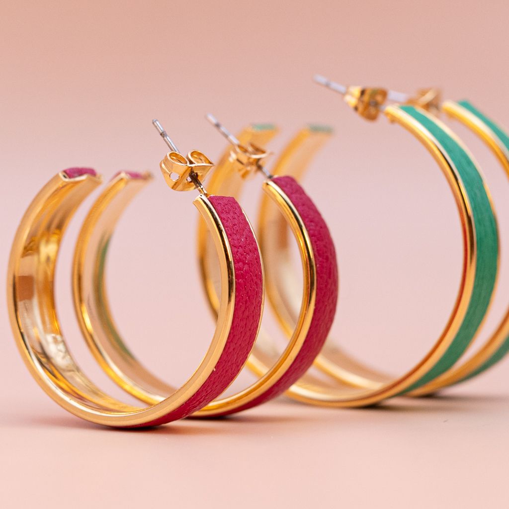 Colorful enamel hoop earrings in gold, pink, and green tones arranged in a row.