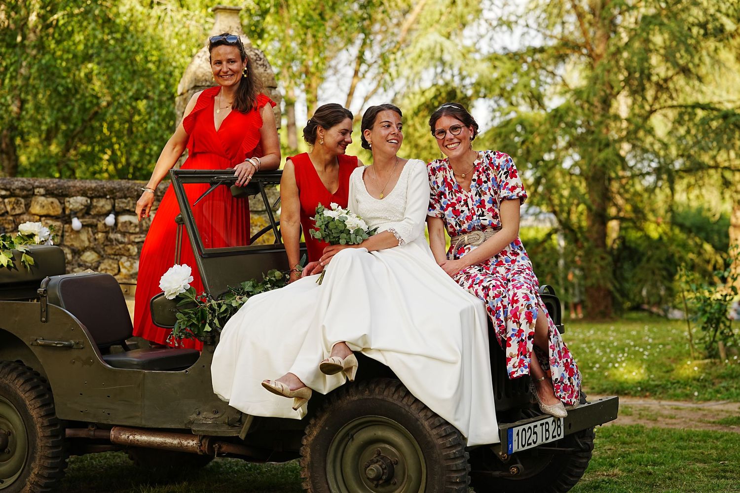 People gathered outdoors near vintage vehicles during a sunny celebration.