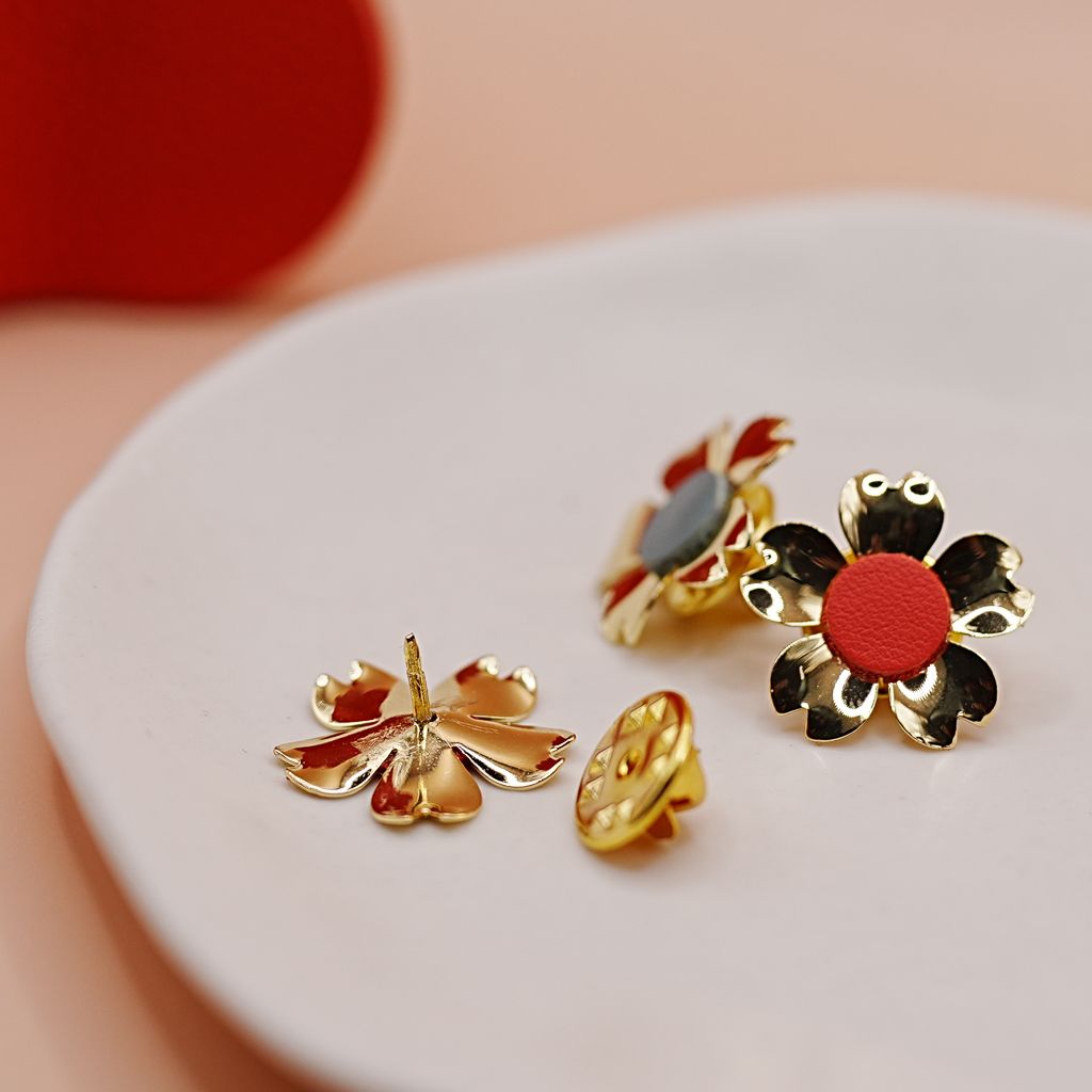 Small decorative enamel pins featuring floral and nature designs displayed on white surface.