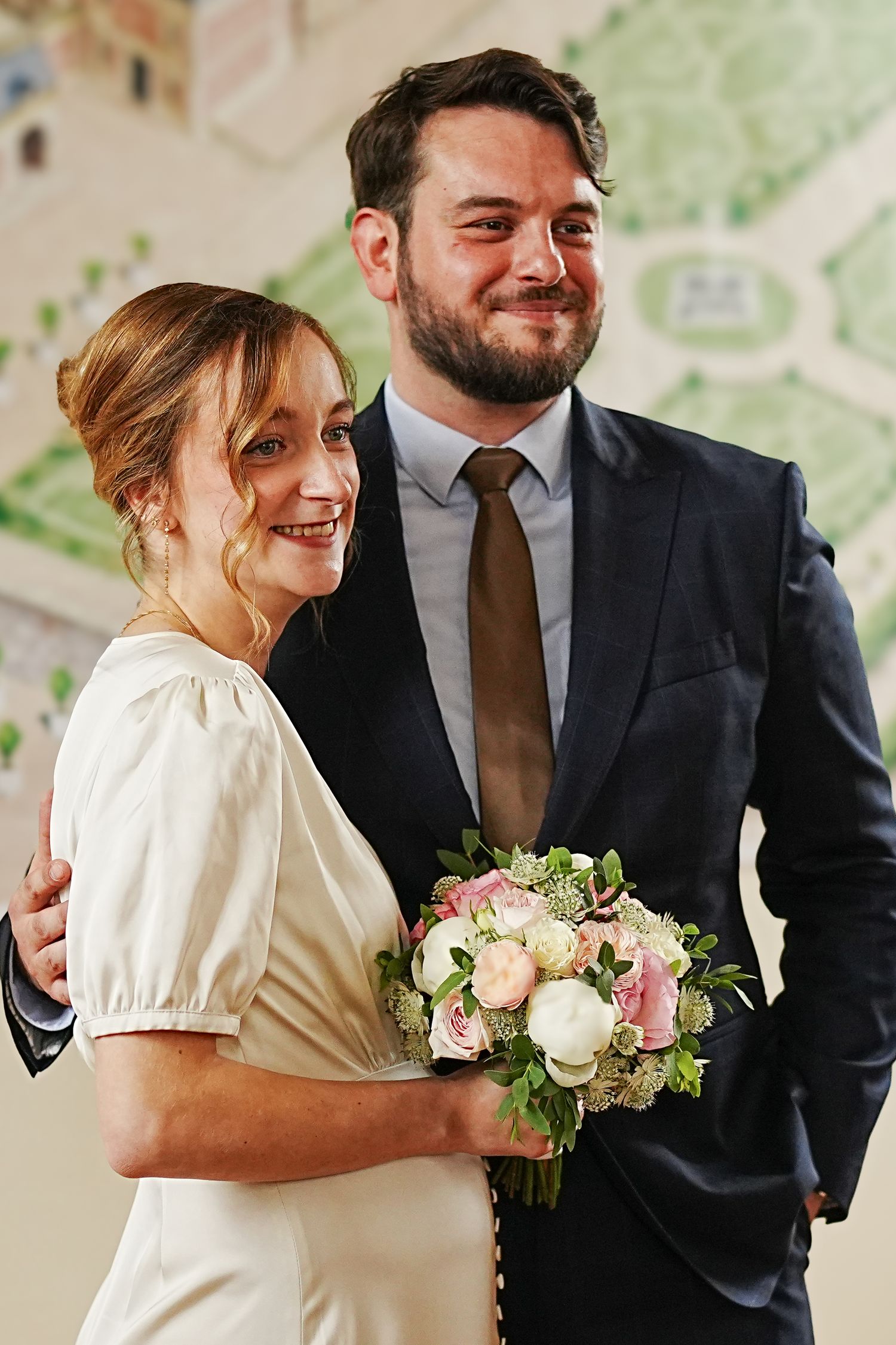 A couple shares a joyful moment together while holding a delicate bouquet of white and pink flowers.