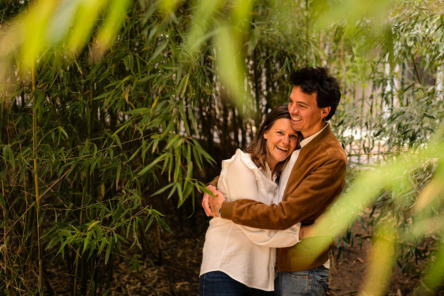 Romantic moment captured through foliage in natural outdoor setting.