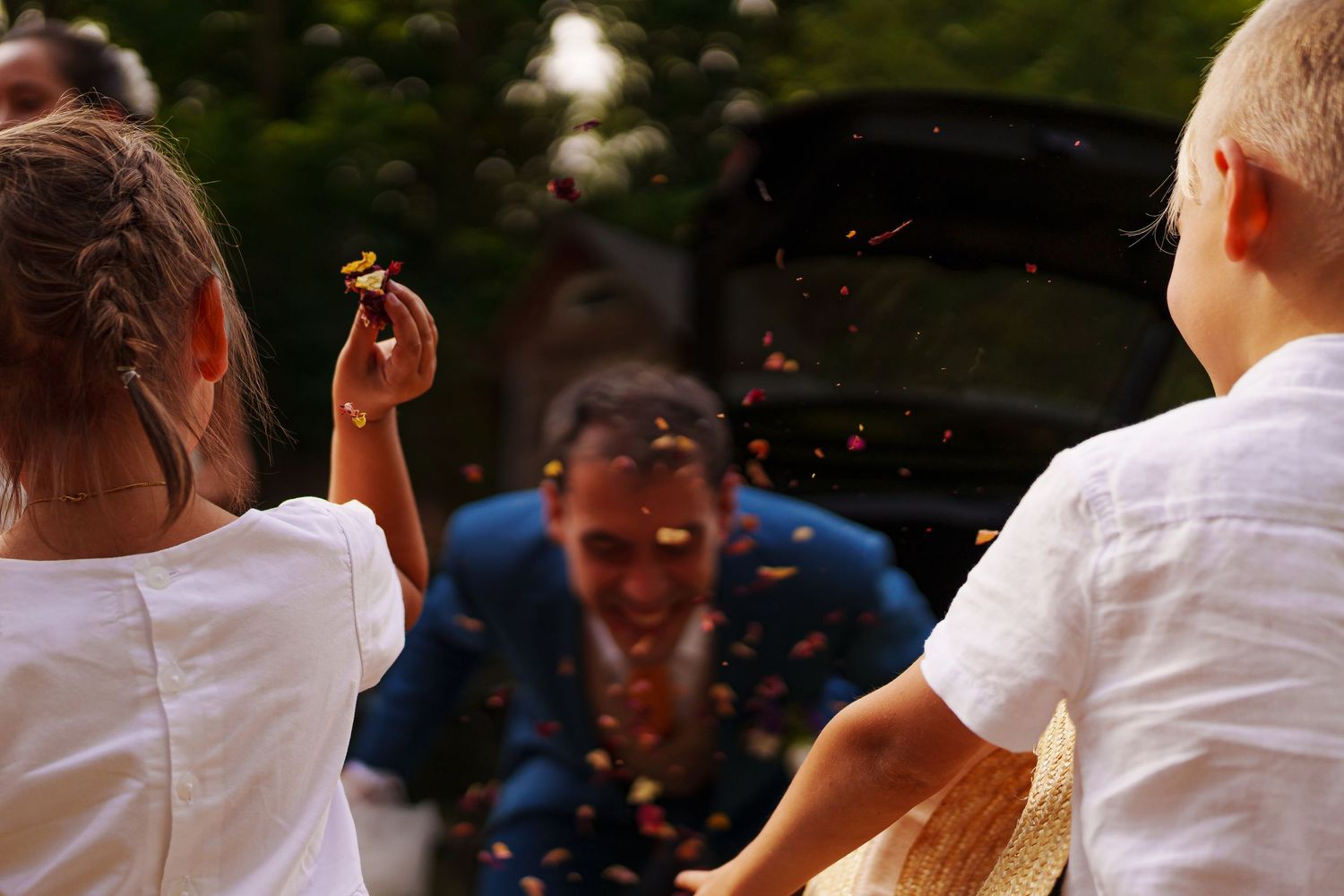 People dancing and celebrating at an outdoor party or celebration with string lights in the background.