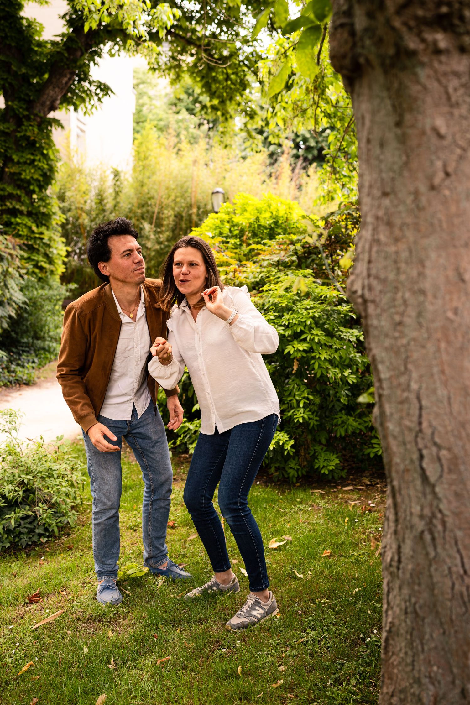 A playful couple enjoying a sunny day in a lush garden setting.