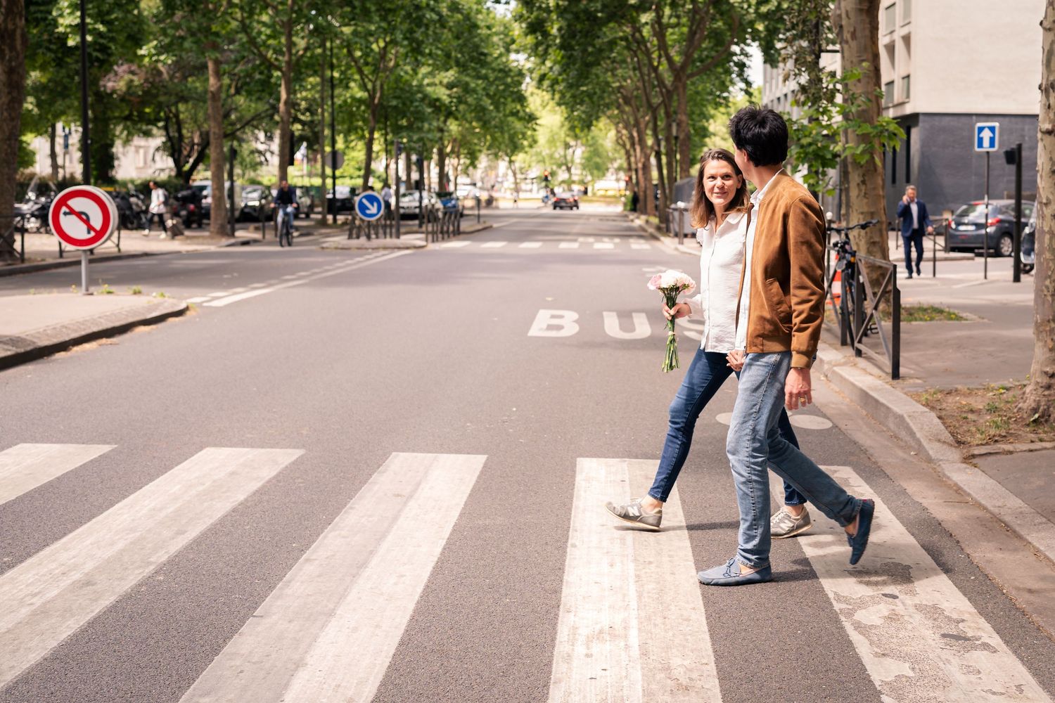 A couple crossing a street together in an urban setting.