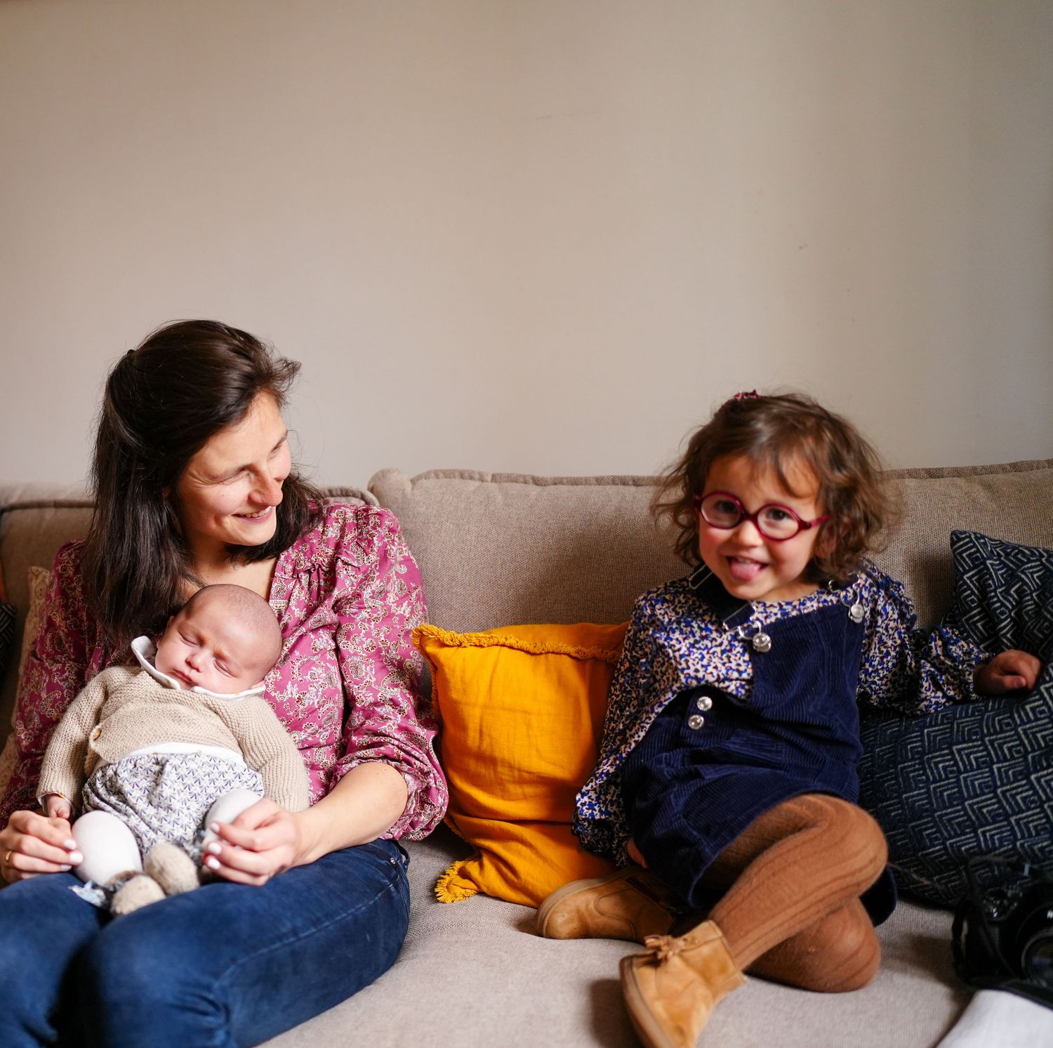Intimate family moments captured on couch with orange pillows and blue decor.