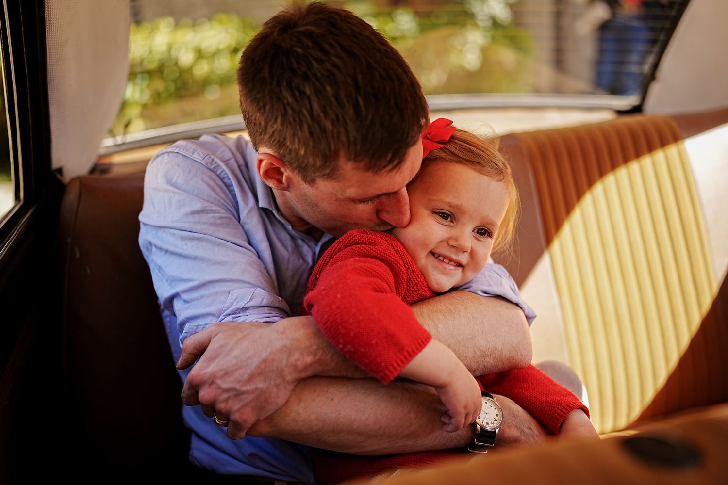 Two figures share a tender moment while sitting together on a couch.