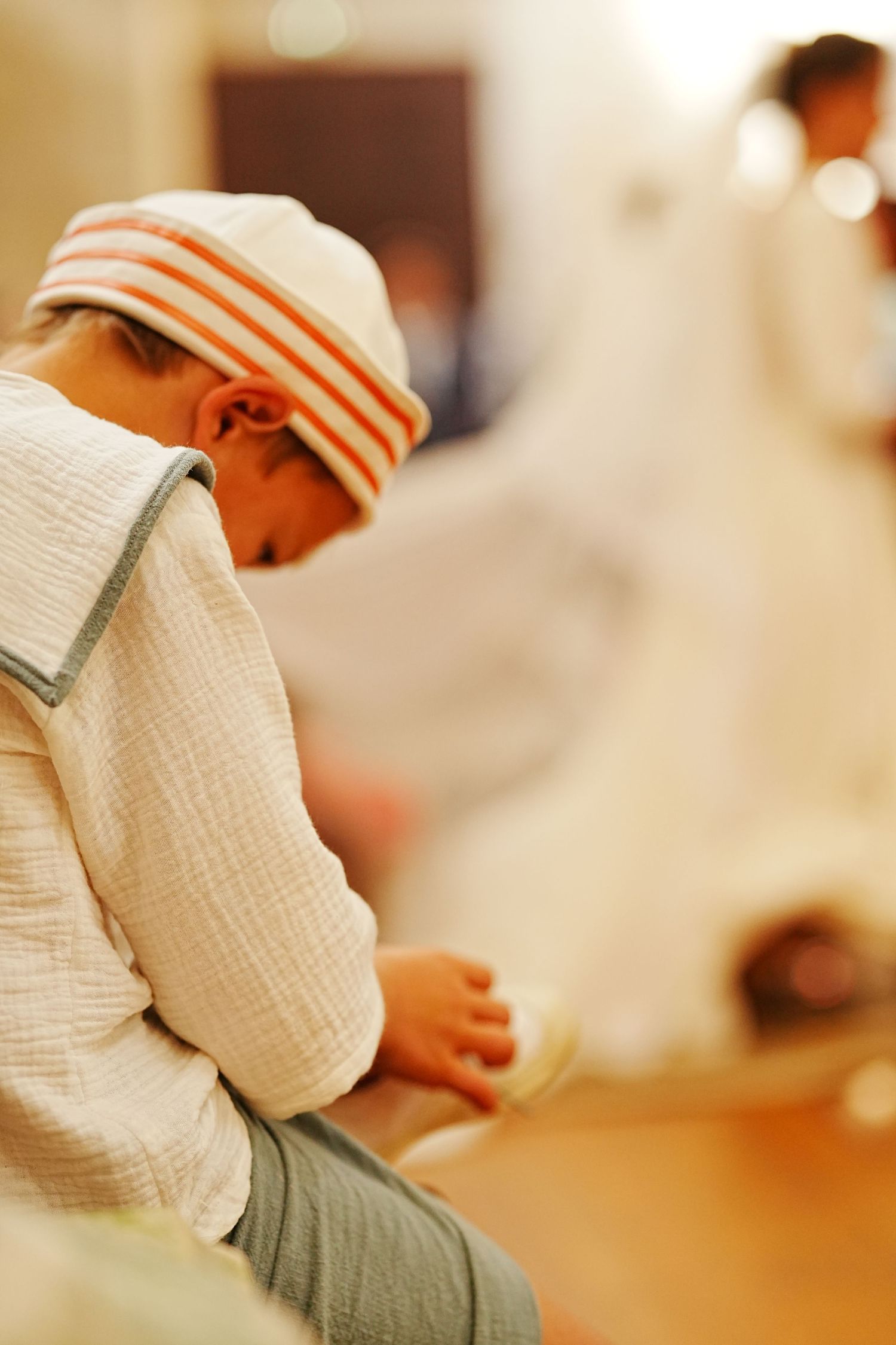 Person in white traditional religious attire kneeling in prayer during ceremony.