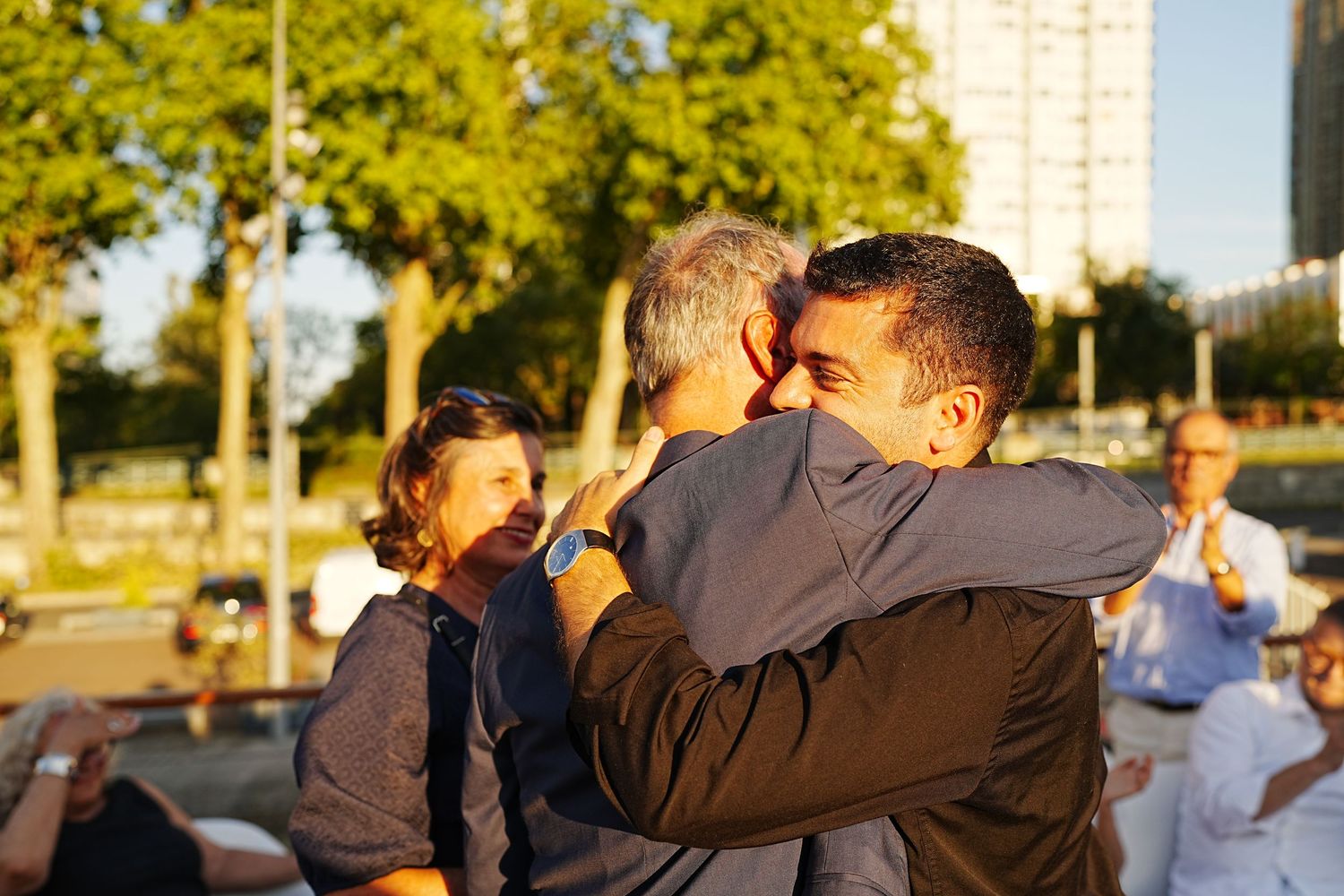 People gathered outdoors during golden hour with arms around each other.