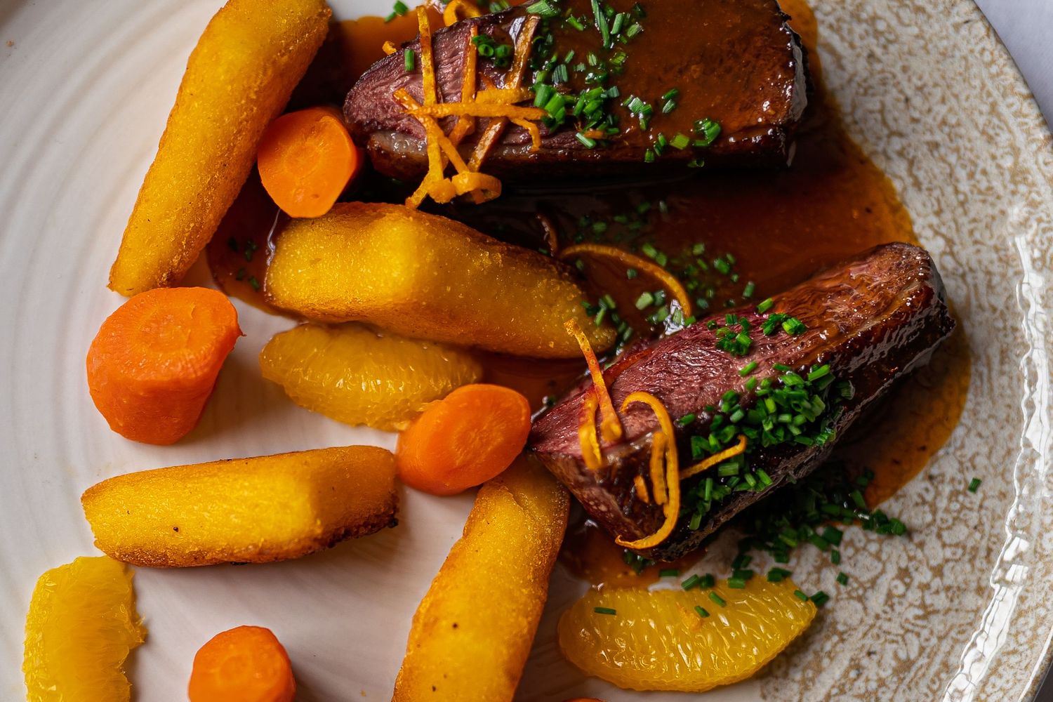Plated meal with roasted carrots and potatoes garnished with fresh herbs.