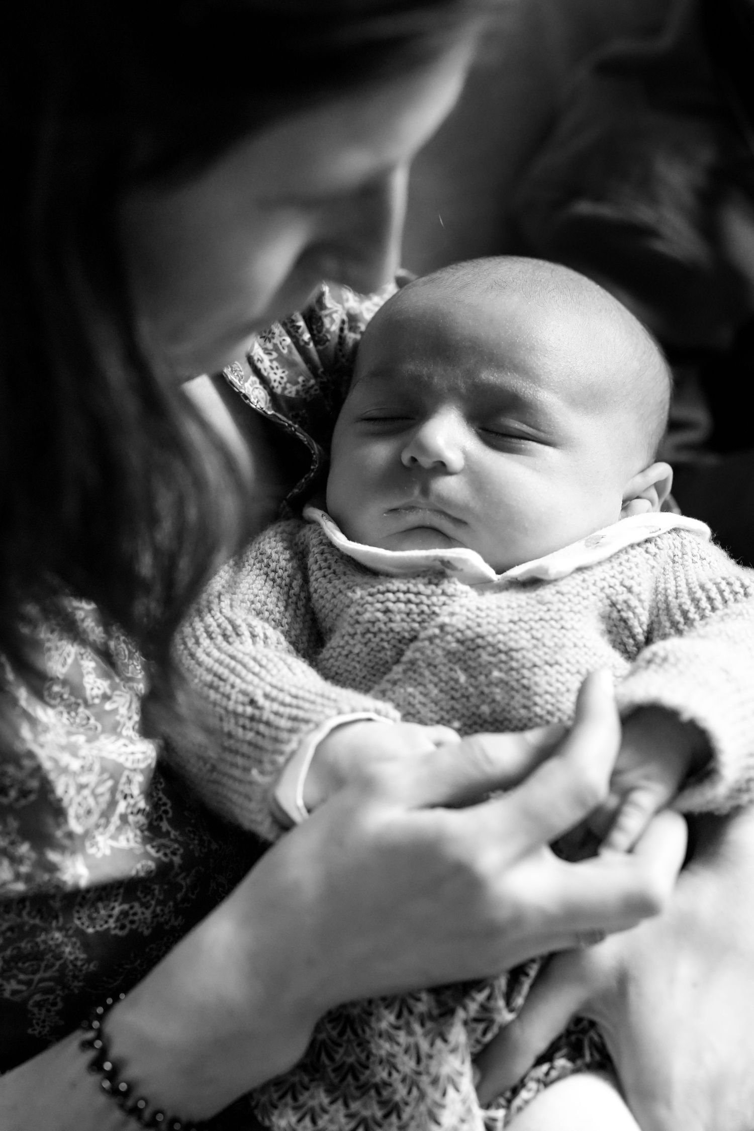 Intimate black and white portrait of newborn baby being cradled.