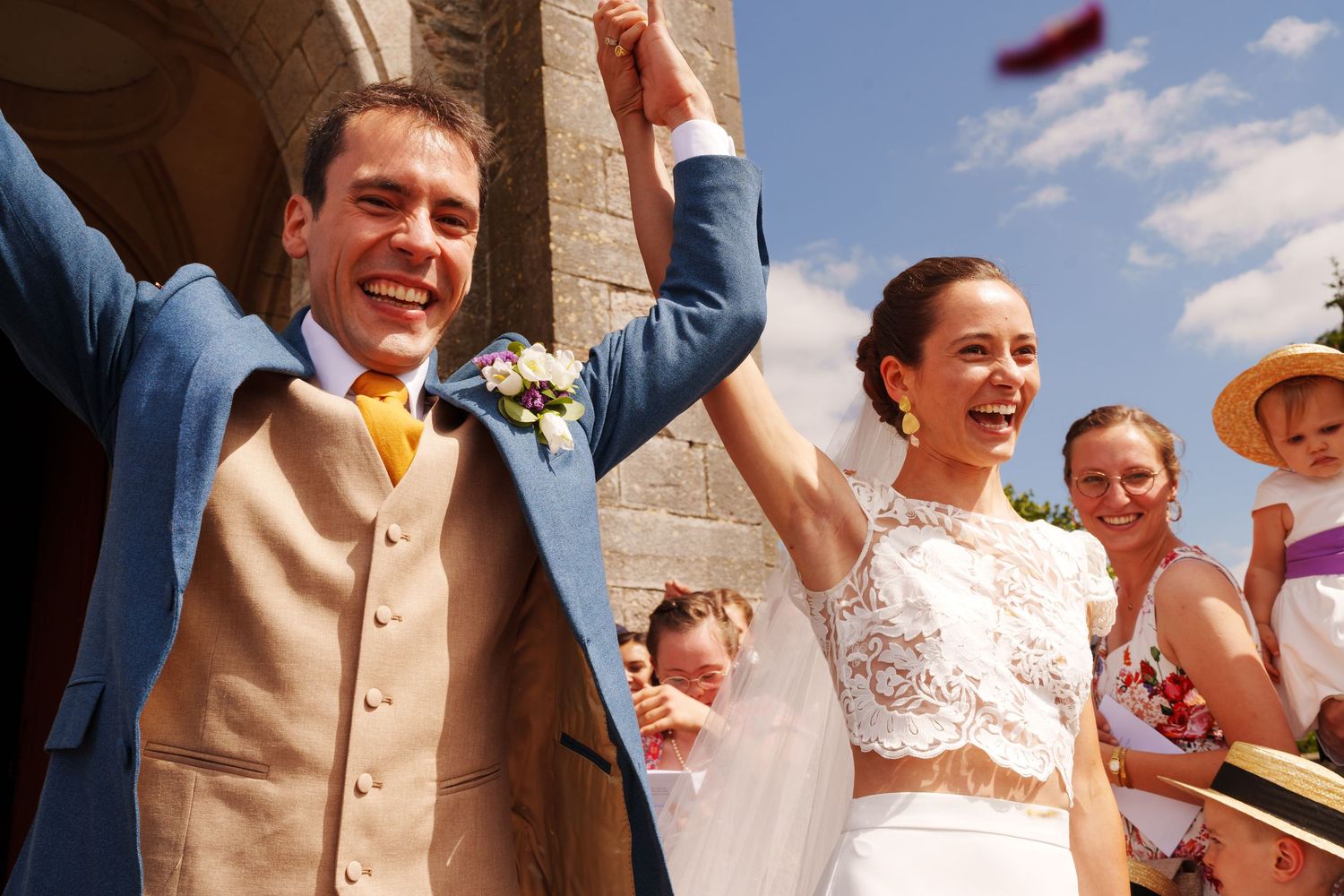 Joyful wedding celebration outside historic stone building.