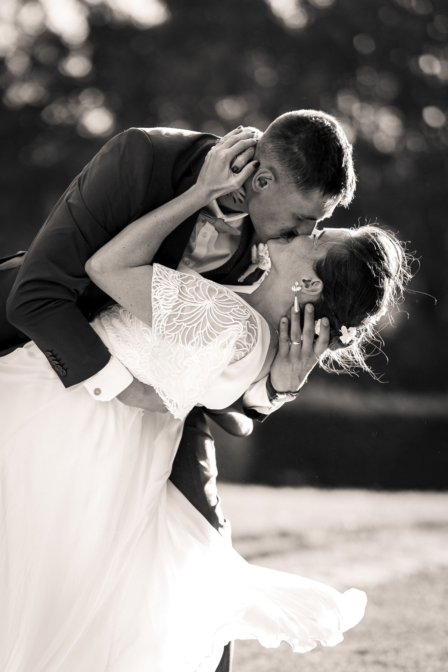 Romantic black and white wedding photo series showing a couple in an intimate dip kiss outdoors.