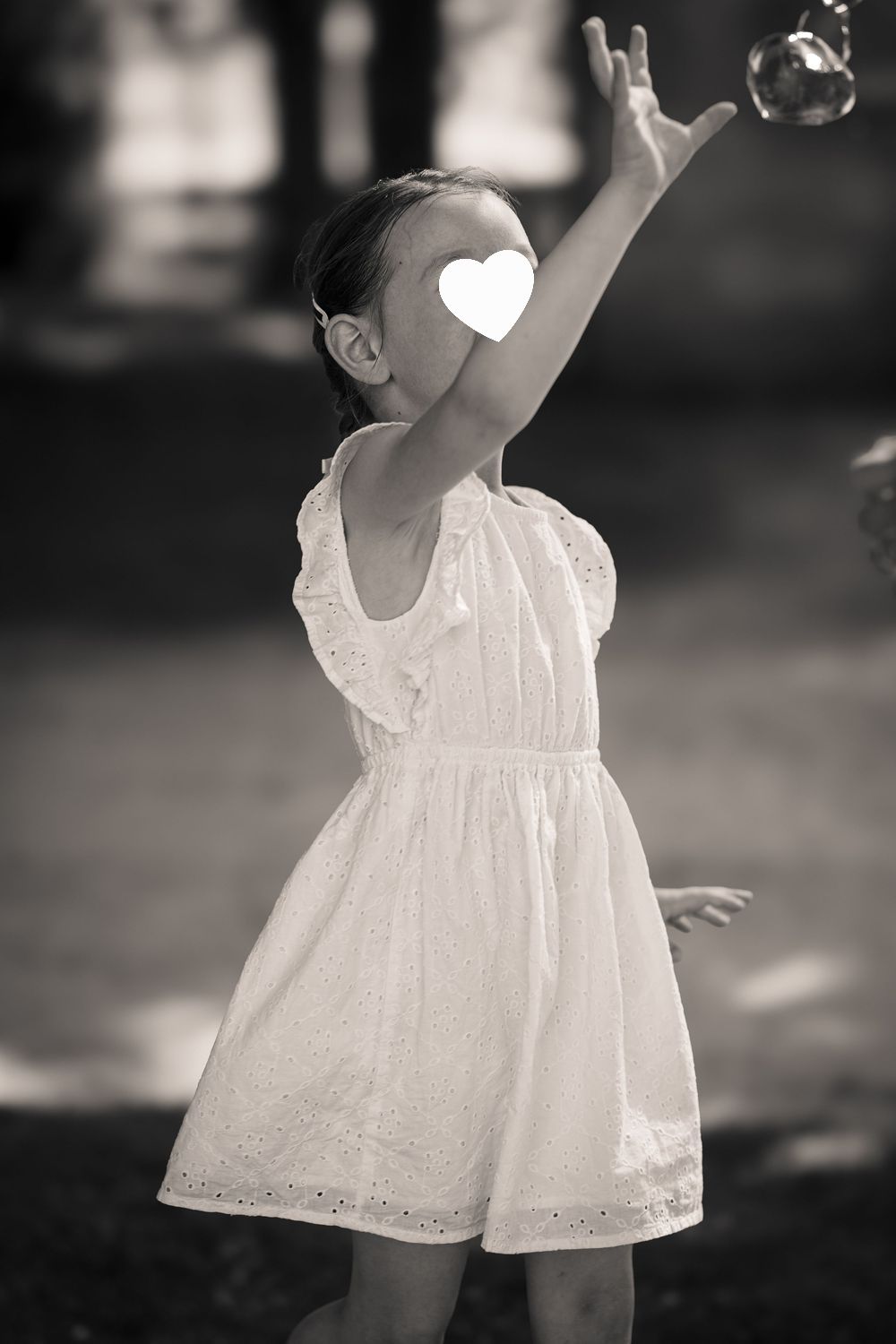 A child in a white lace dress twirls playfully in a series of black and white photographs showing graceful movement.