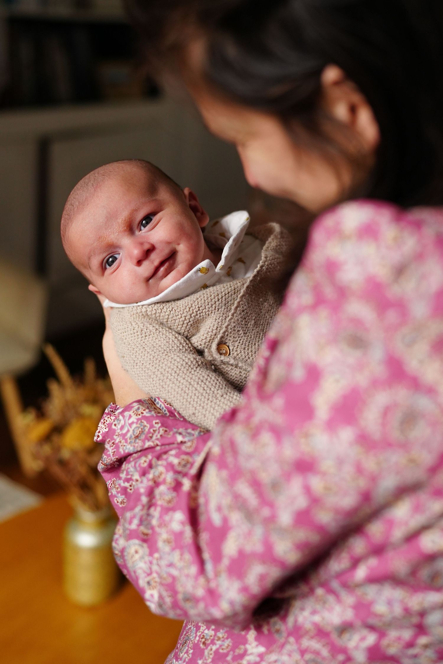 Baby wearing knit sweater with pink floral pattern in foreground.
