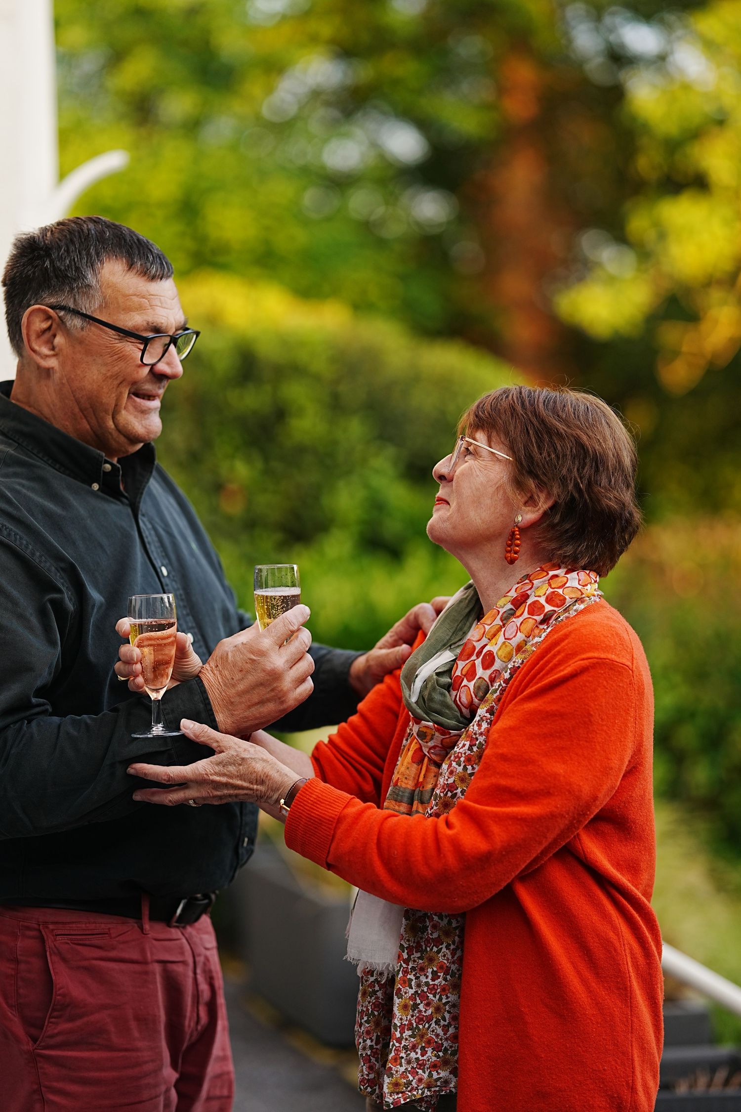Two people share drinks and conversation at outdoor wedding reception.