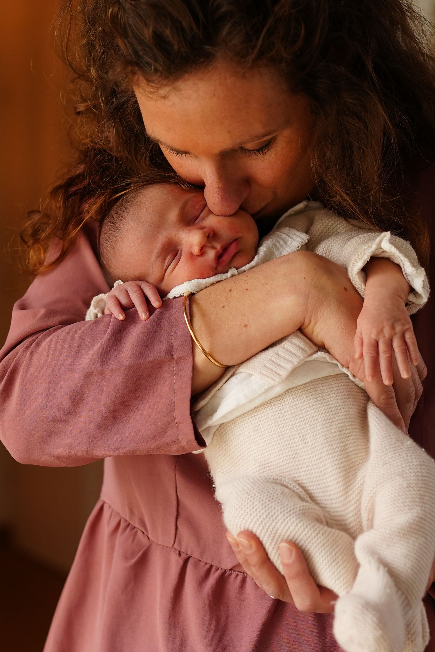 Tender moment between parent and sleeping newborn baby in soft natural lighting.