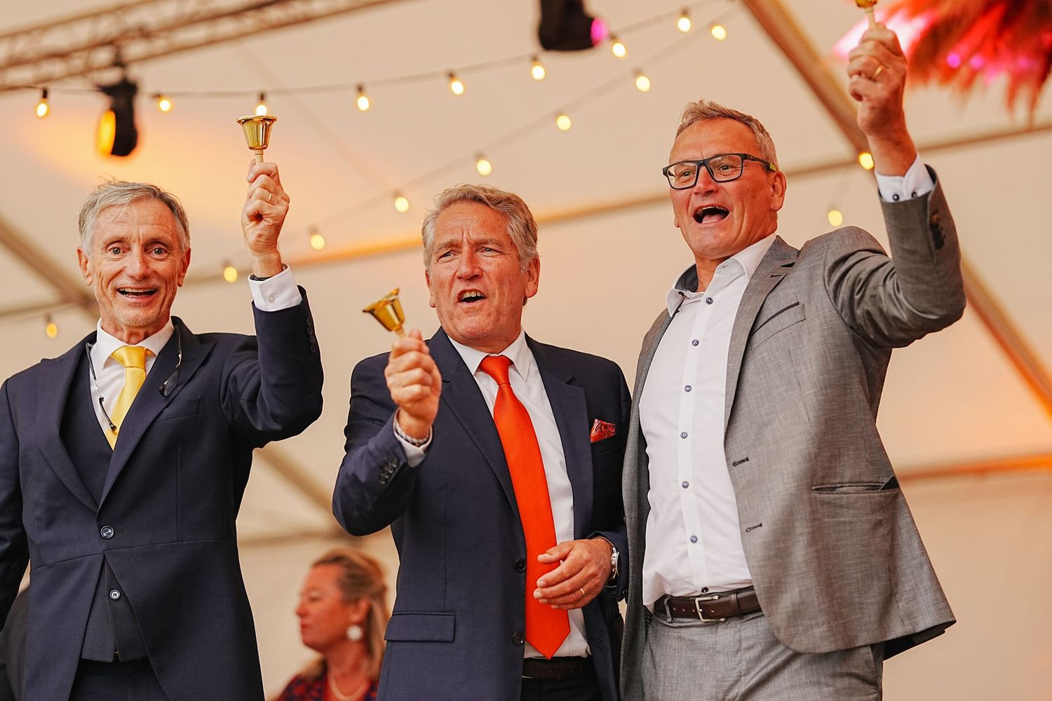 Wedding guests raise their glasses in a celebratory toast at an elegant indoor reception.
