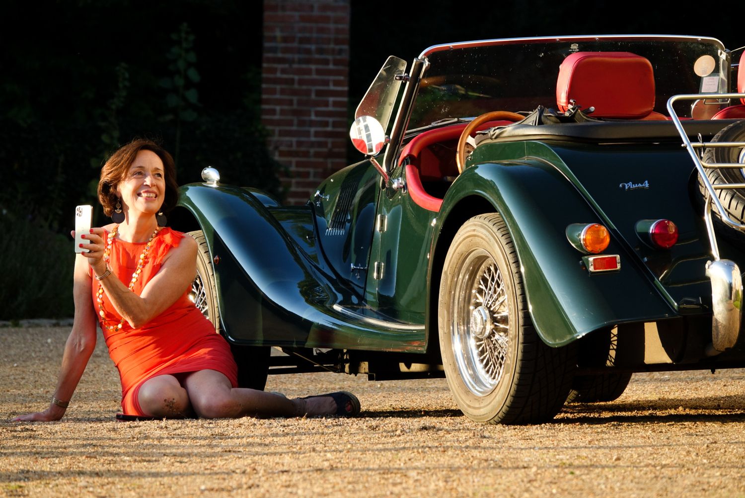 Vintage cars lined up at an outdoor event with people sitting nearby.