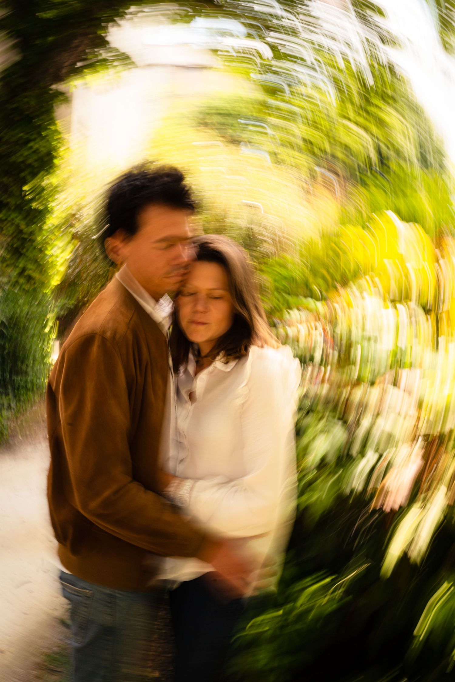 An artistic motion-blur photo of a couple embracing in a garden.