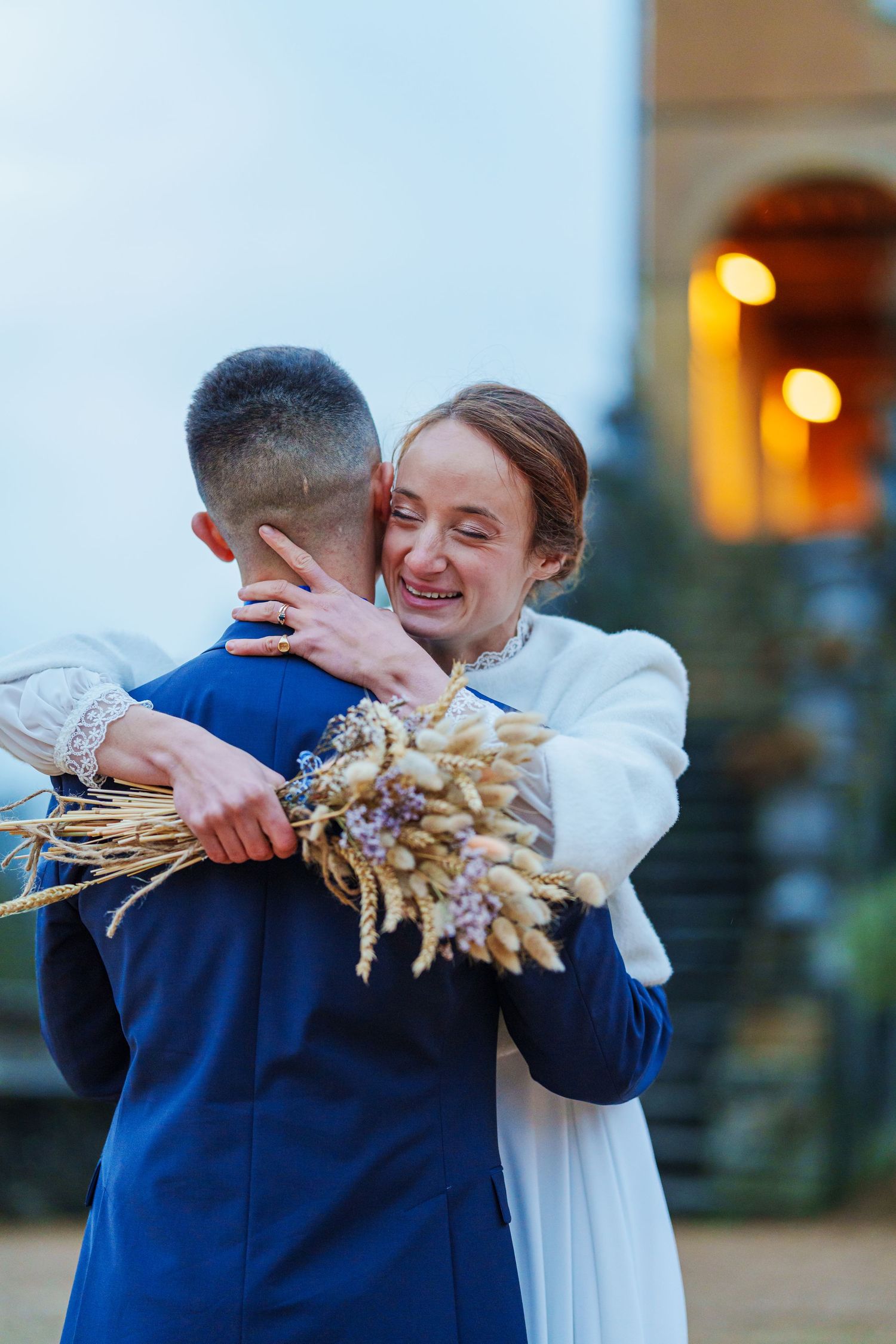 Joyful wedding moment captured outdoors with warm evening lighting and natural decor elements.
