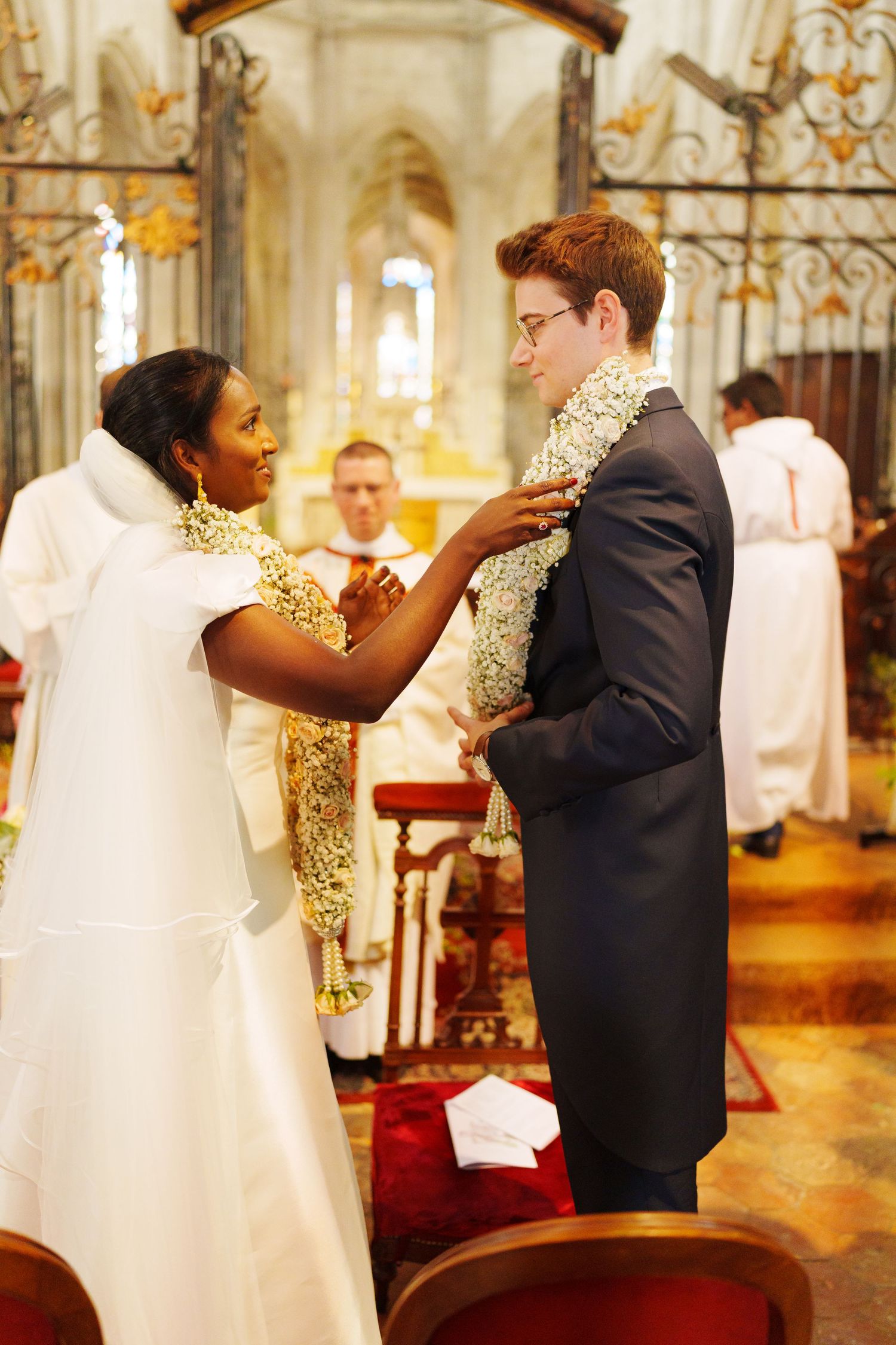 A wedding ceremony in a grand cathedral with traditional garland exchange.