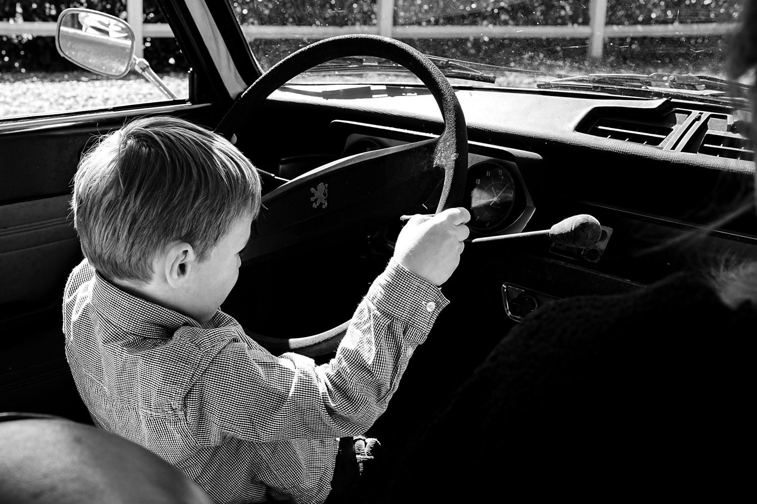 Interior view of a classic car dashboard and steering wheel in monochrome.