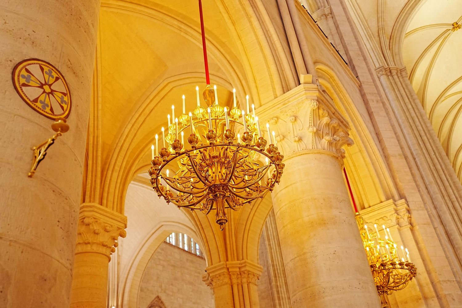 Ornate cathedral interior with golden chandeliers and vaulted ceilings illuminated in warm lighting.