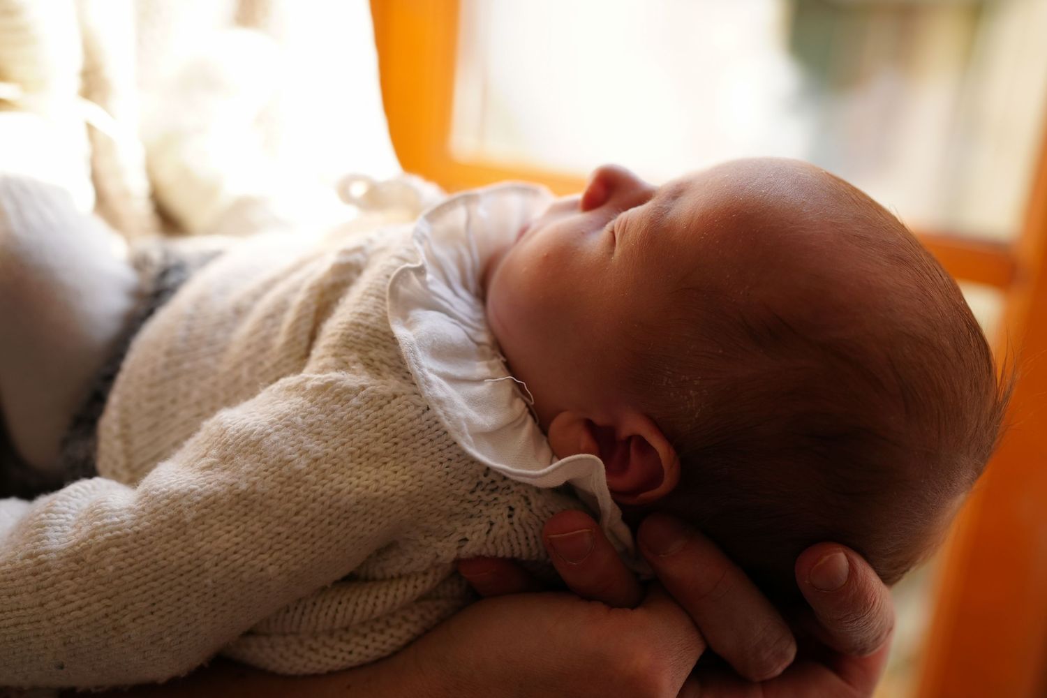 A series of close-up shots showing a sleeping newborn baby swaddled in white blankets.