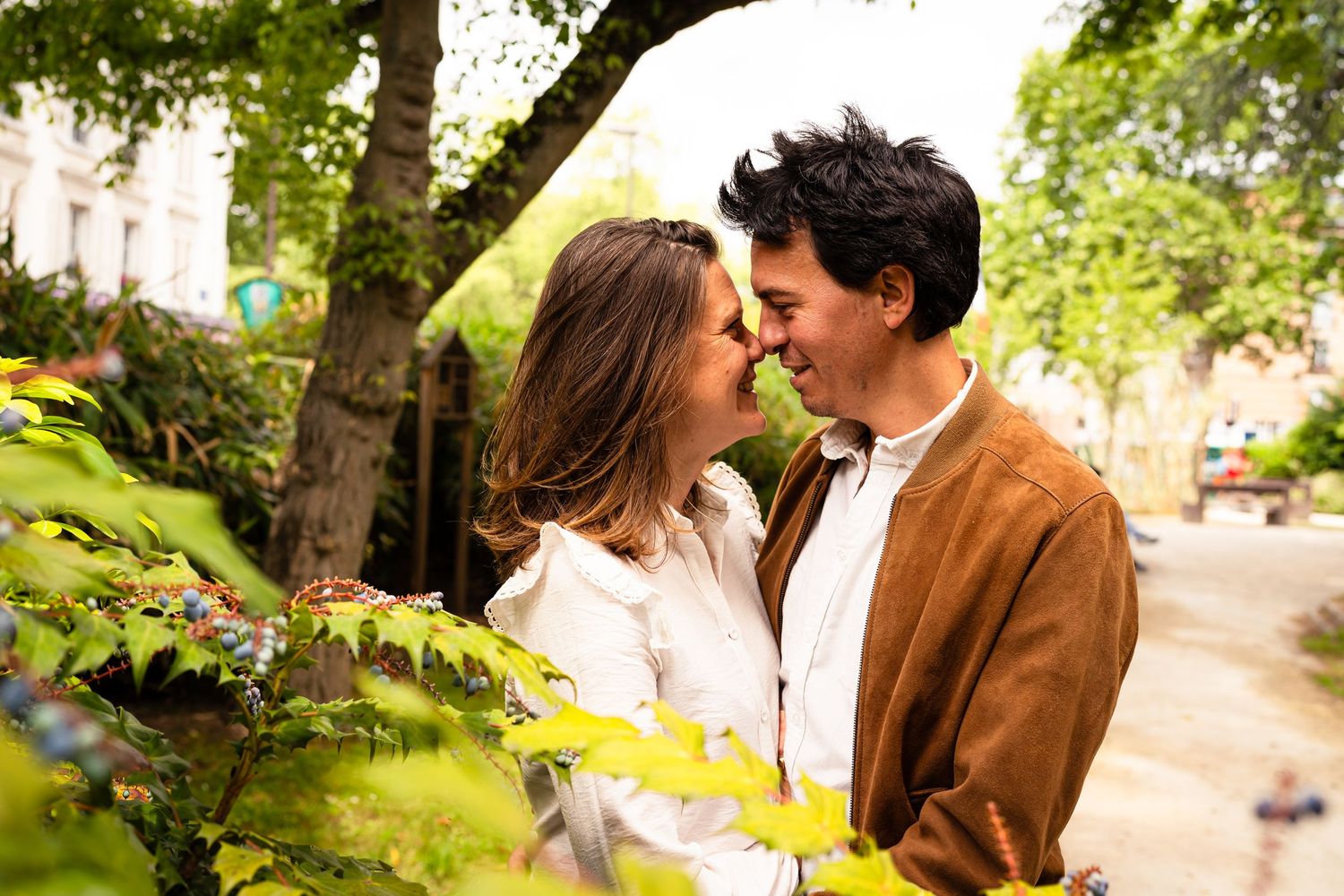 Romantic couple sharing an intimate moment in a lush garden setting with natural sunlight filtering through trees.
