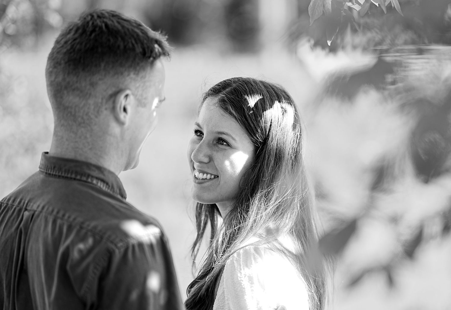 Black and white portrait of a couple sharing an intimate moment outdoors.