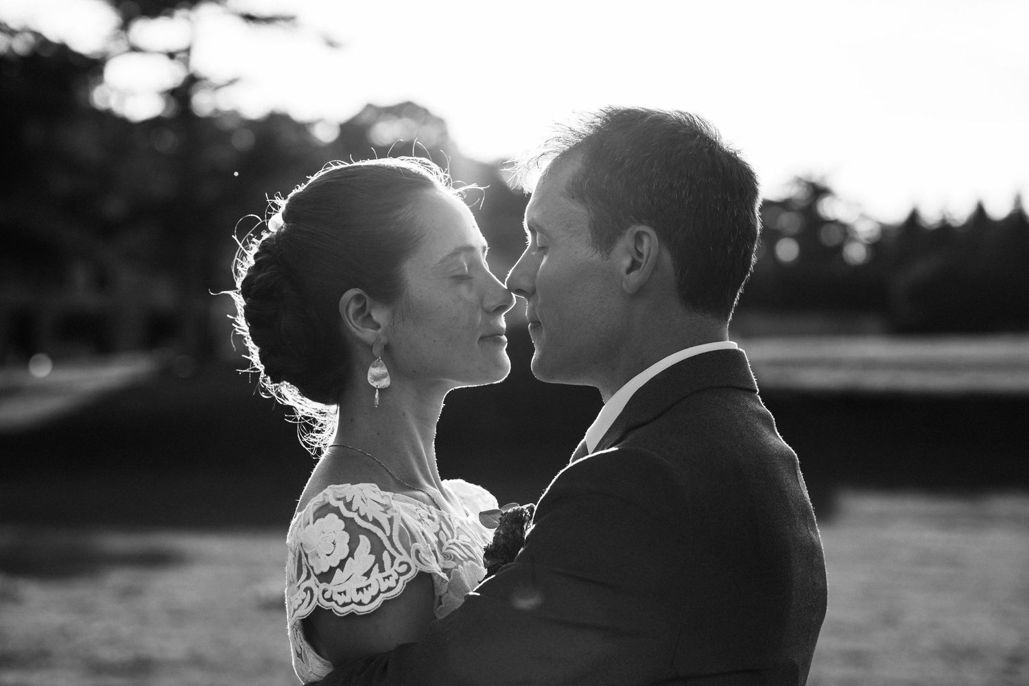 A romantic black and white portrait of a couple sharing an intimate moment at sunset.