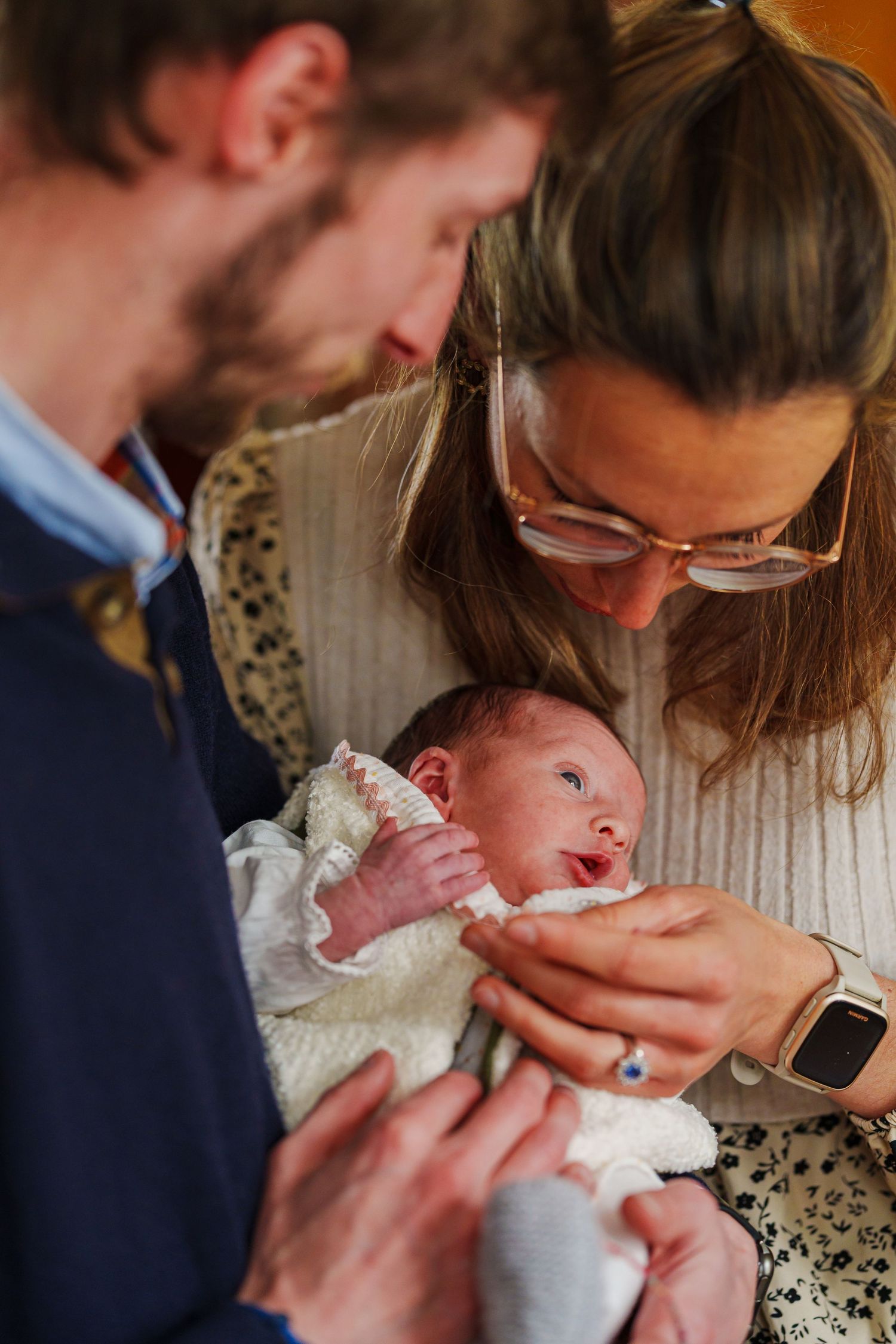 Parents lovingly gazing at their newborn baby, mother holding infant while father looks on warmly.