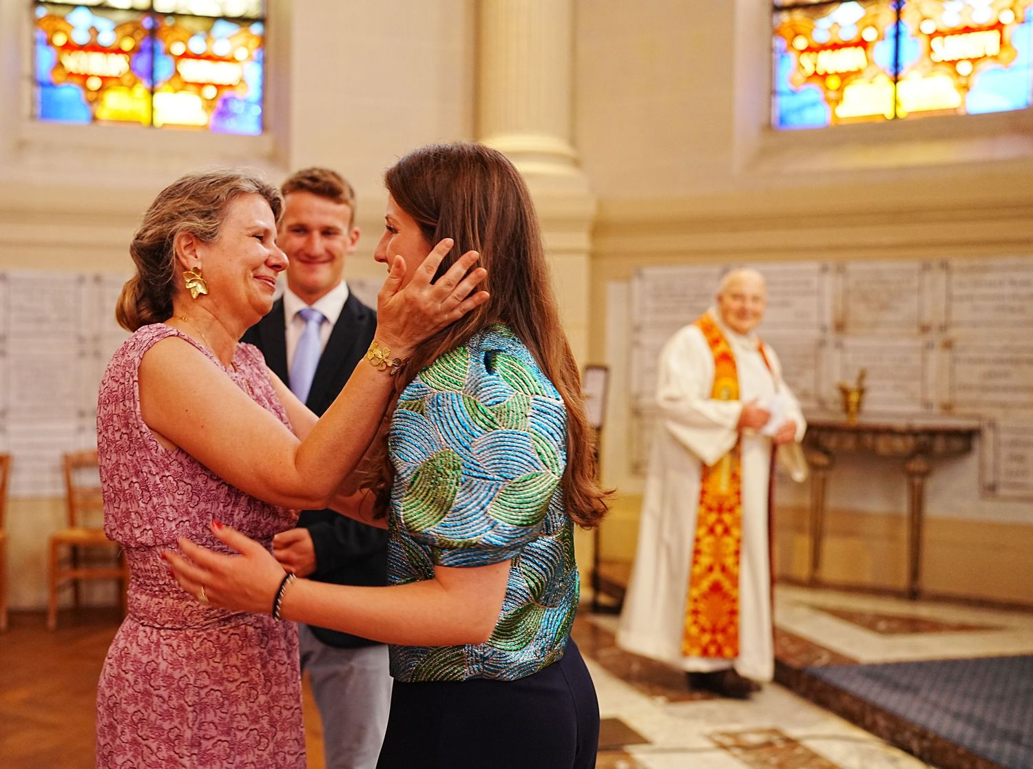 Wedding celebration inside church with colorful stained glass windows in background.