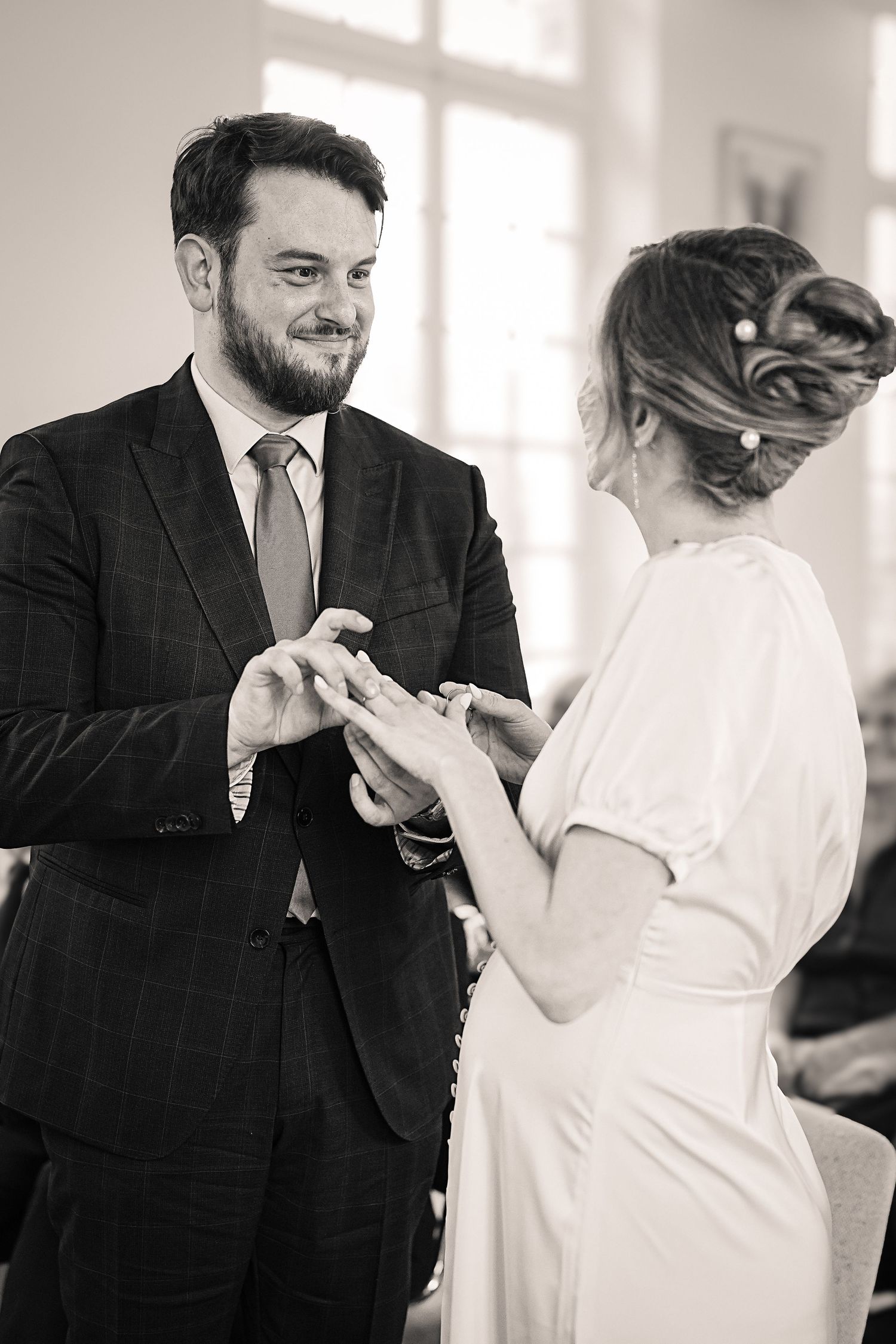 A couple dancing together in a bright indoor space wearing formal attire.