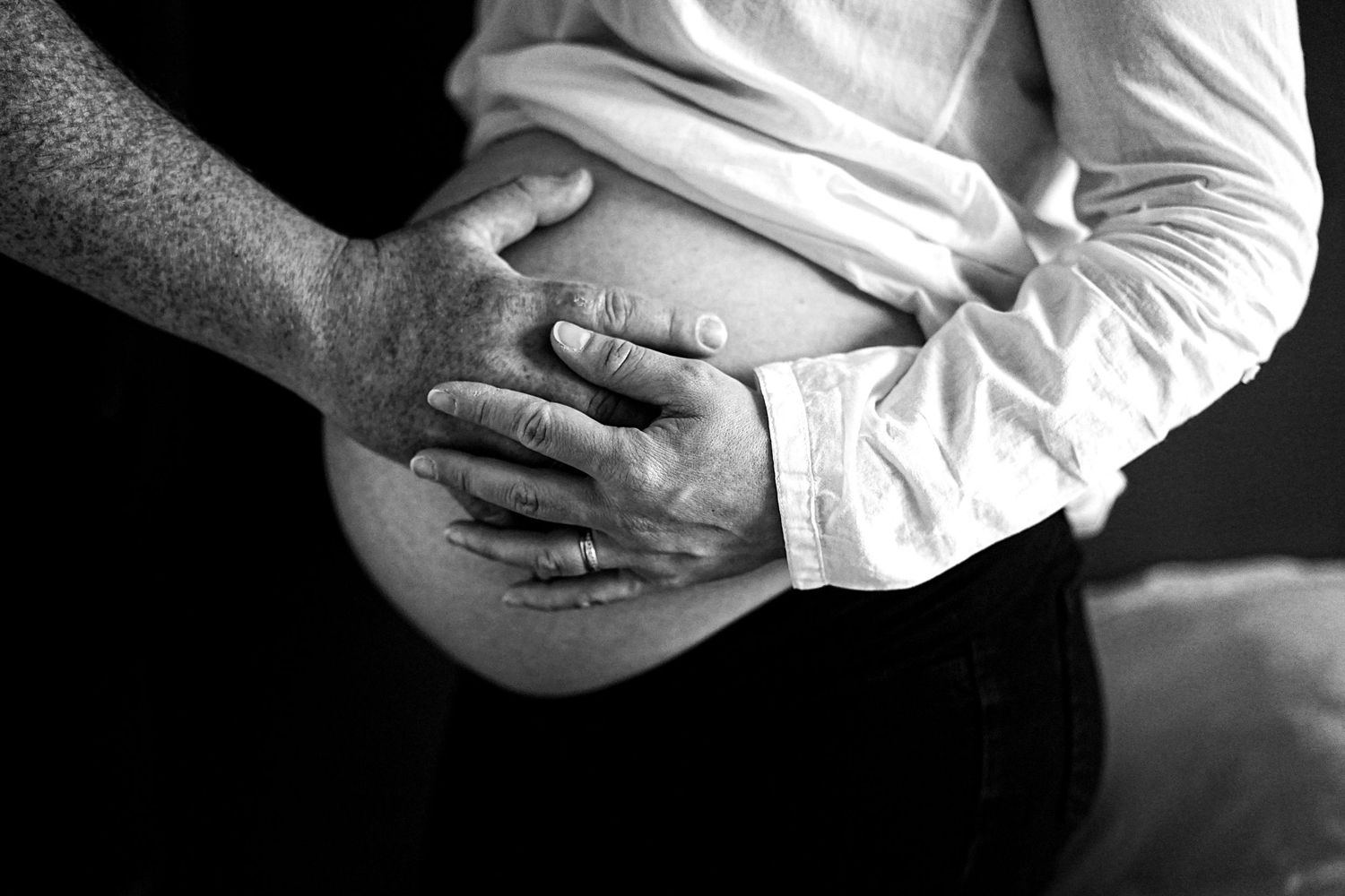 Close-up series of hands gently cradling a newborn baby in black and white.