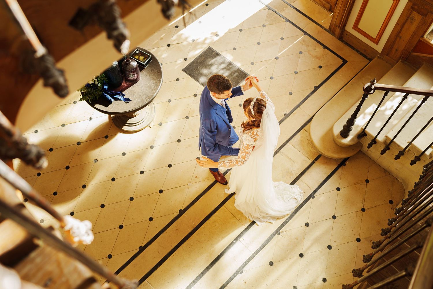 Wedding celebration captured from above showing dancing on patterned ballroom floor.