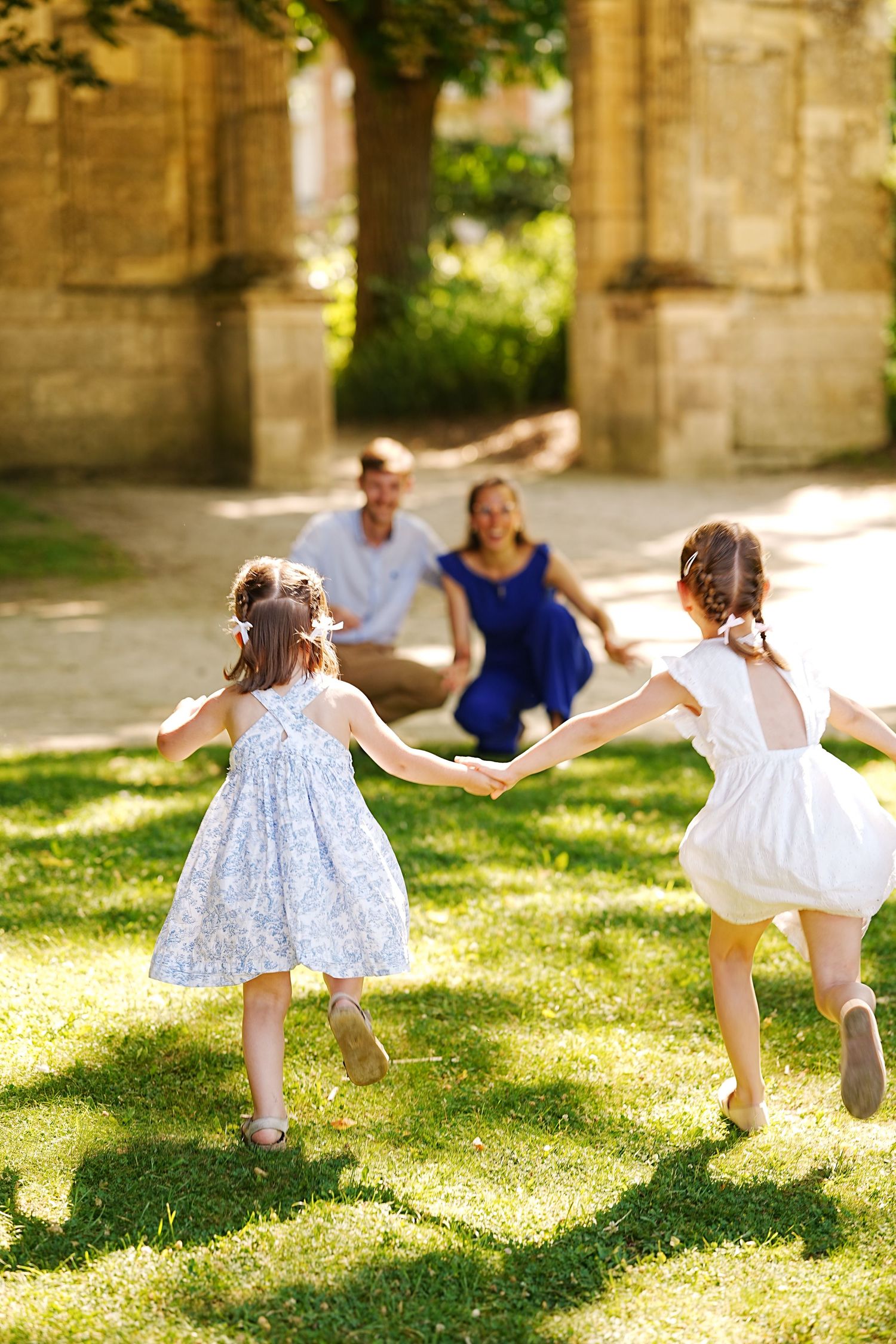 Children running and playing on grass near stone pillars in a joyful summer scene.
