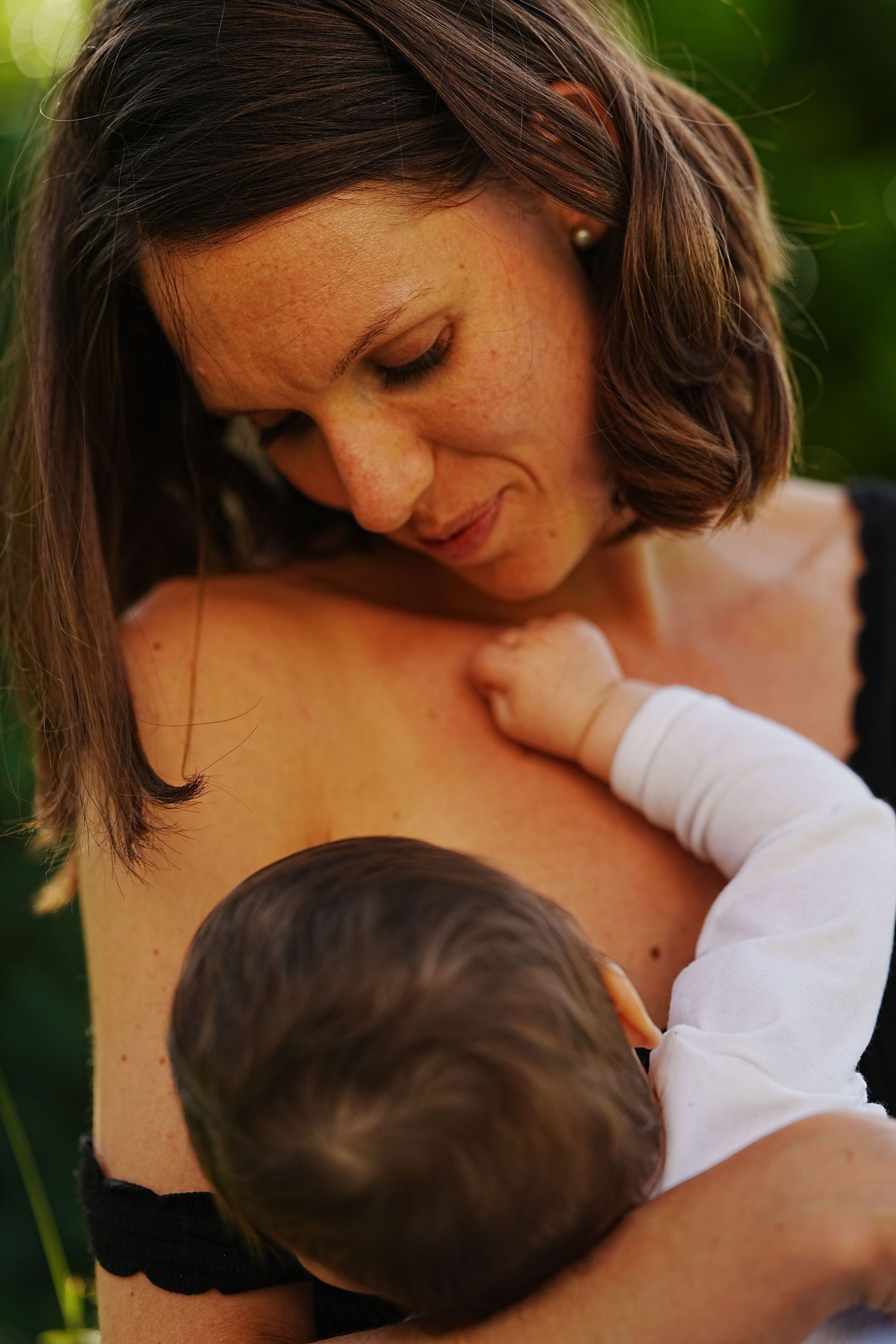 Tender moment between parent and baby in natural outdoor setting.