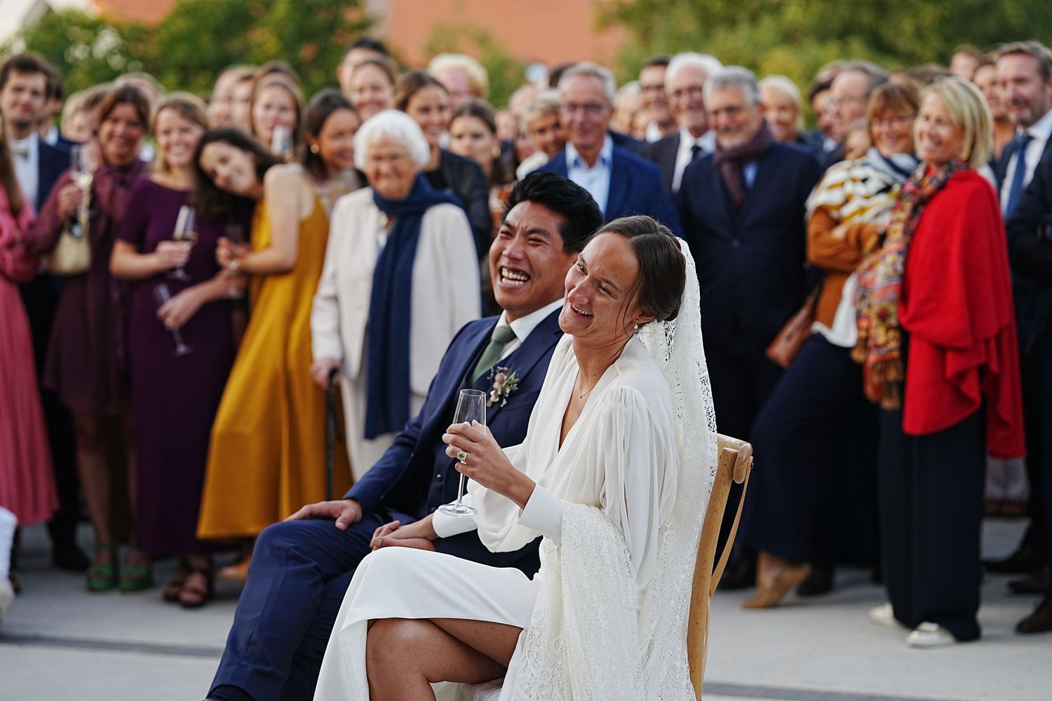 Wedding guests gather outdoors to celebrate and cheer during a joyful reception ceremony.
