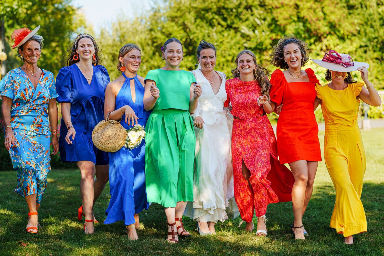 A group in colorful dresses sits together on grass in a vibrant outdoor photo collage.