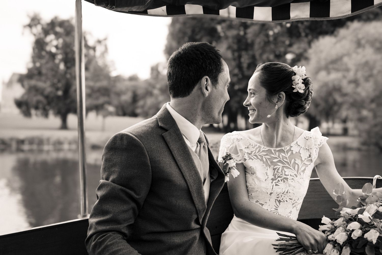A black and white photo of a couple sharing an intimate moment on a boat by the lake.