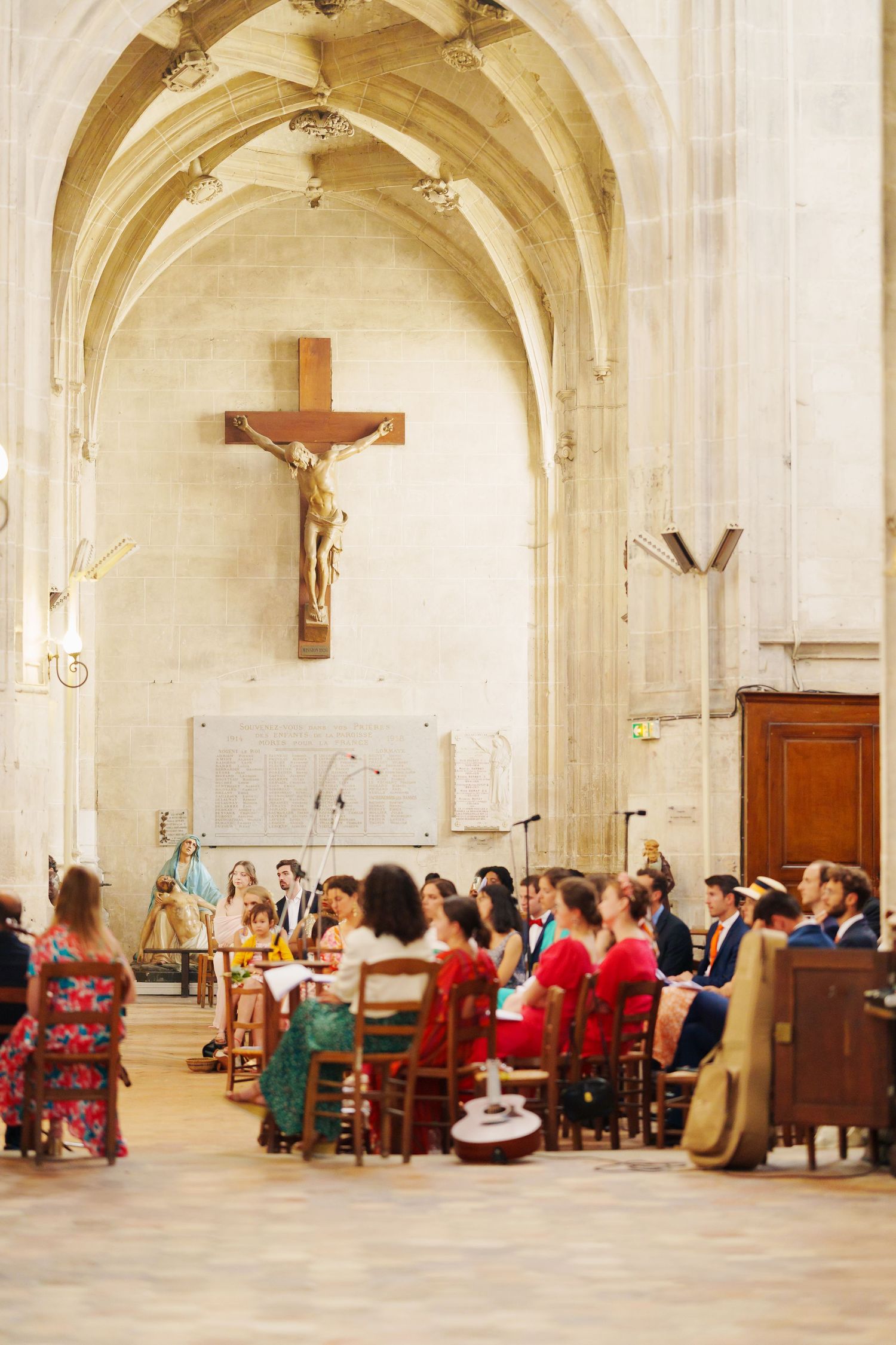 Interior of historic church with crucifix and guests seated for wedding ceremony.