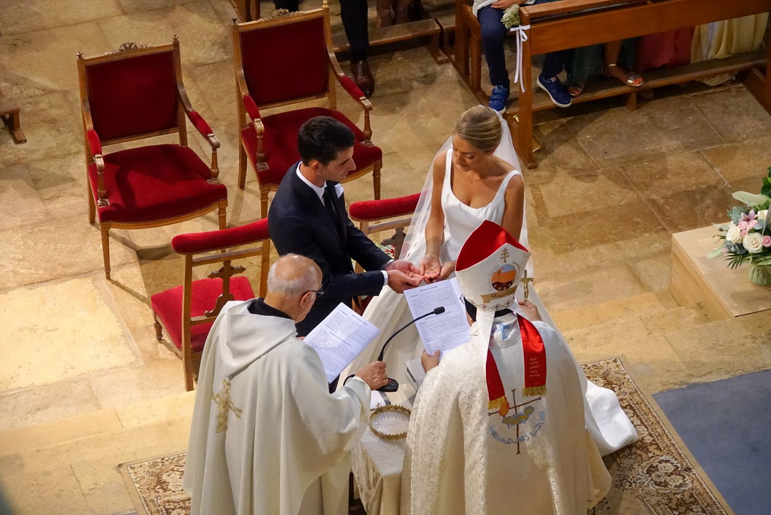 Religious ceremony in a church with clergy in white robes performing a traditional ritual.