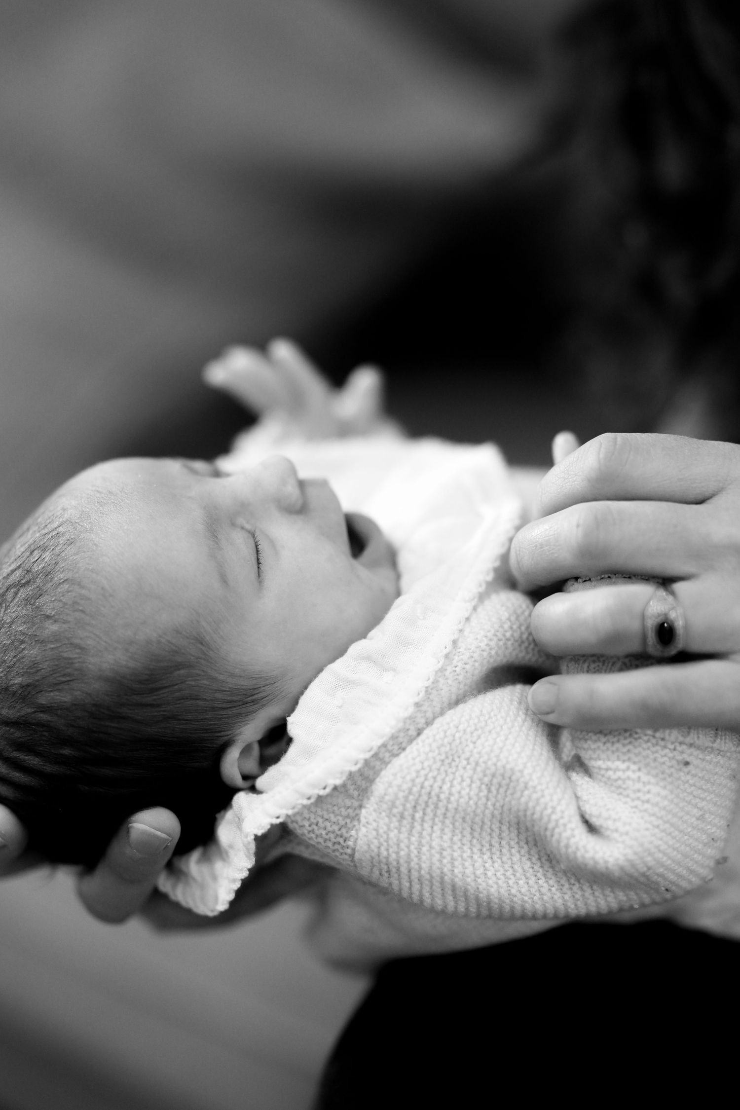 Black and white portrait of peaceful sleeping infant wrapped in soft blanket.