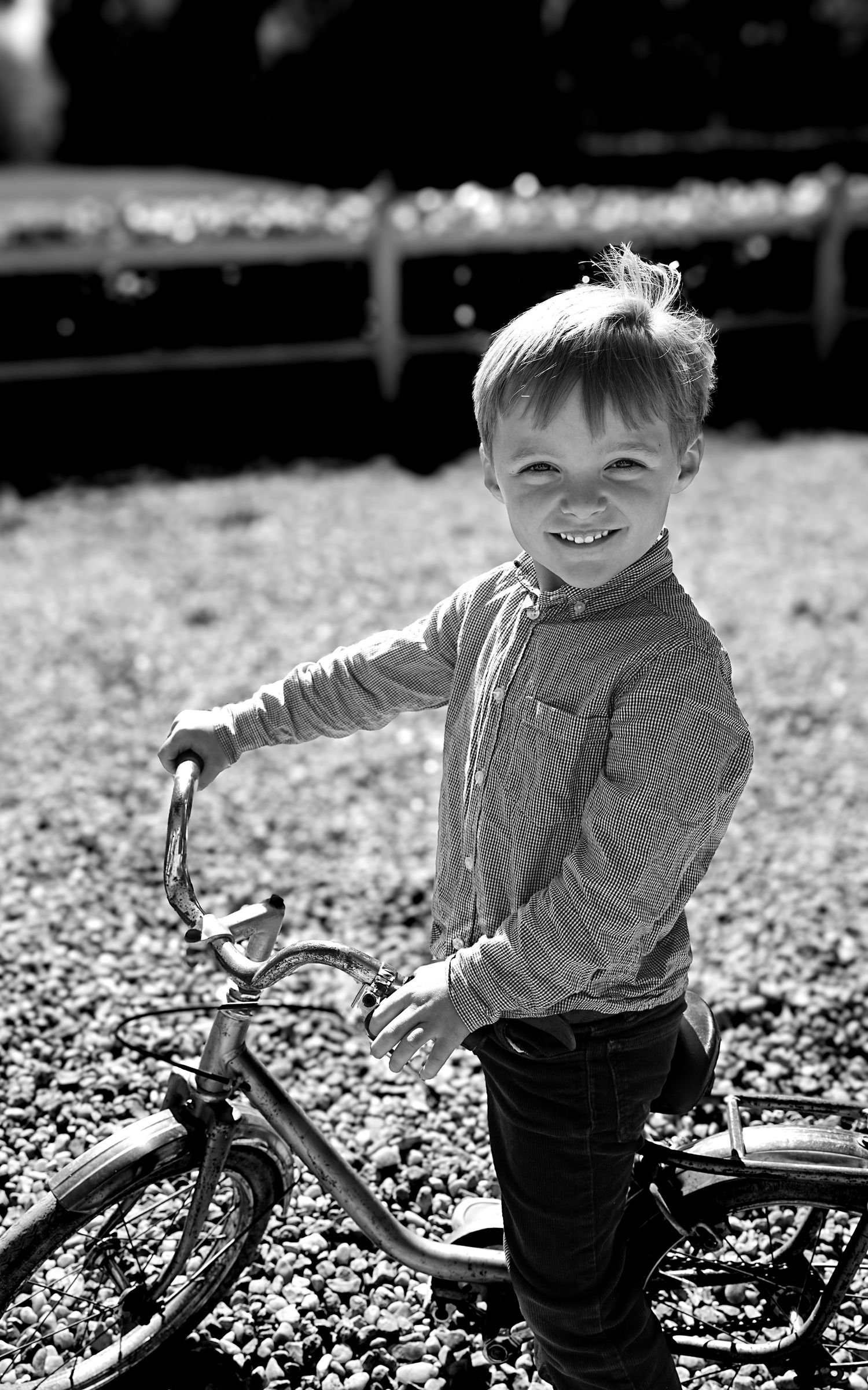 Black and white photos of a small figure with a vintage bicycle outdoors.
