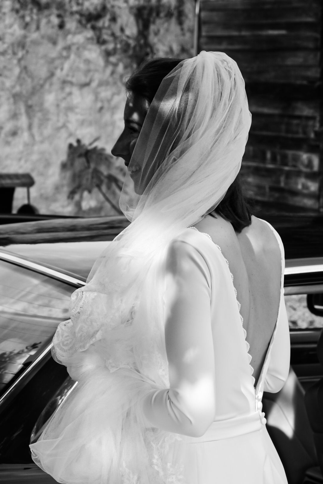 A bride in a white wedding dress and veil photographed from behind.