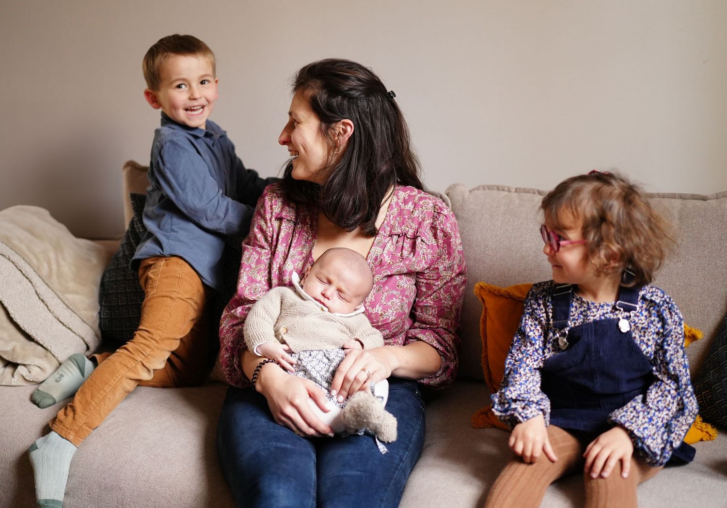 Family sitting together on a beige couch in casual clothing.