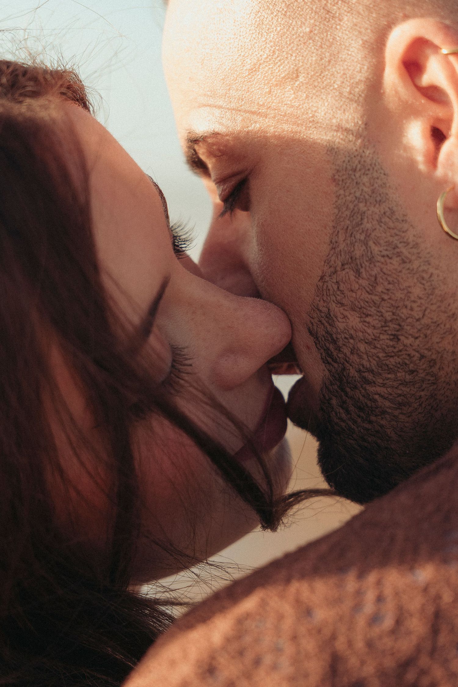 Close-up of a romantic couple sharing a tender kiss in warm sunlight.