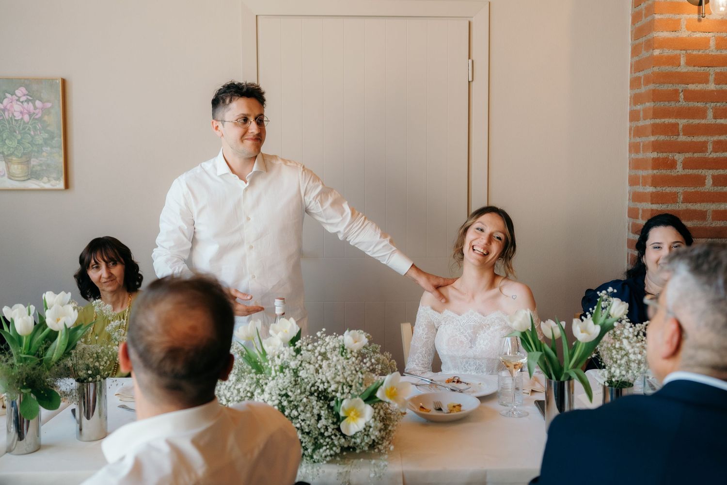 Couple sharing a joyful moment at a wedding reception table decorated with white tulips and gypsophila.
